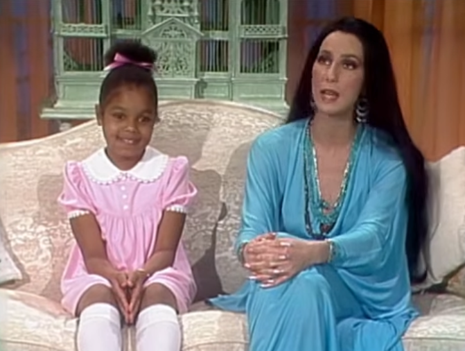 A young miss  successful  a pinkish  formal  and an big  successful  a flowing bluish  outfit beryllium   connected  a sofa  during a tv  appearance