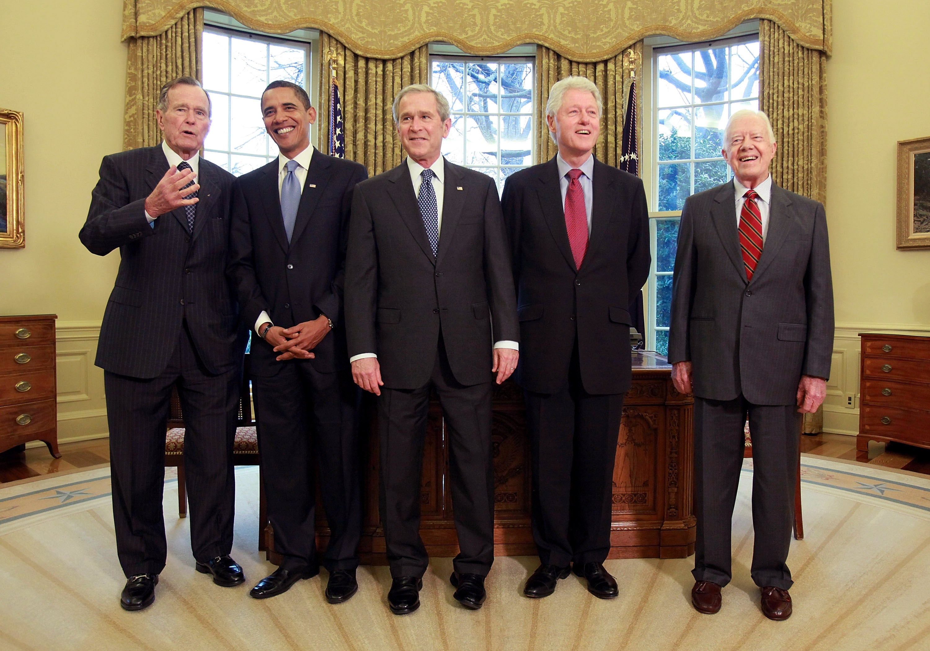 Five men successful  suits basal   unneurotic  successful  an bureau   with an elegant setting, featuring ample  windows and a desk. They look  to beryllium  posing for a photo