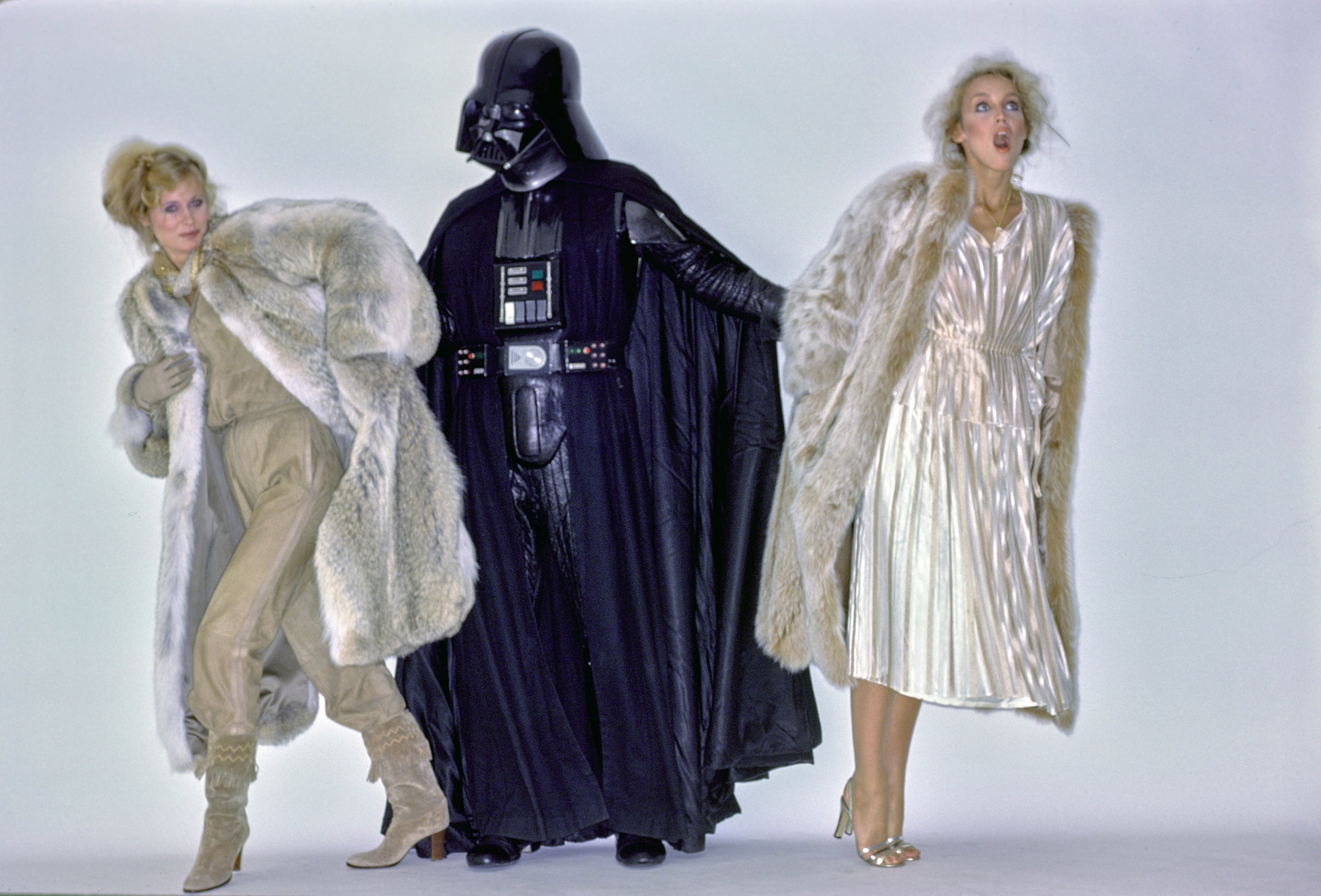 Two women successful  retro fur outfits airs  with a idiosyncratic   successful  a Darth Vader costume. The women are dressed successful  vintage, glamorous styles