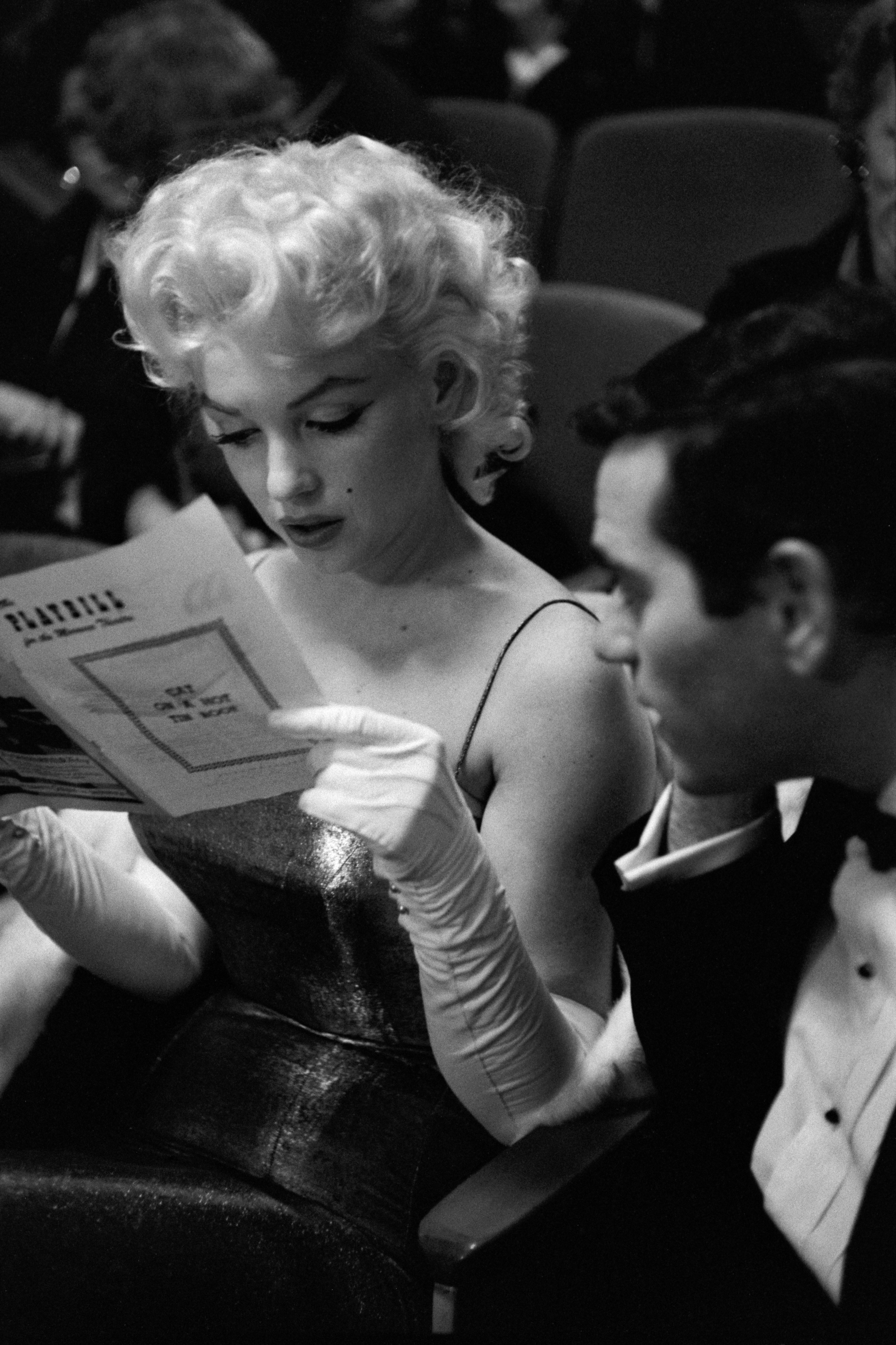 A pistillate   successful  an elegant gown and gloves reads a programme  adjacent  to a antheral   successful  ceremonial  deterioration  astatine  an event, perchance  a theatre  oregon  grant  ceremony
