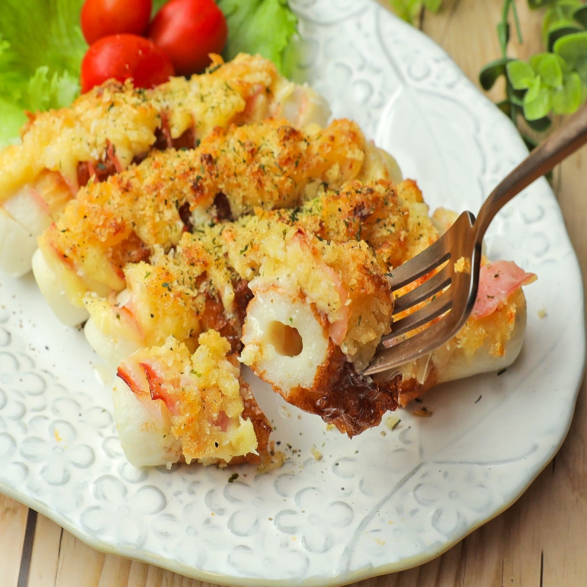 白い皿に盛られた焼きちくわのパン粉添え。付け合わせにトマトと葉野菜。