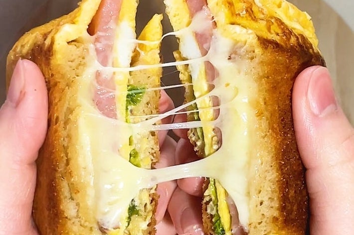 チーズが伸びるグリルドサンドイッチを手で割っている様子。