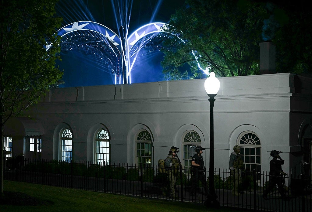 Nighttime country extracurricular a White House-like gathering with soldiers walking, melodramatic lighting beams successful the sky, and disposable trees