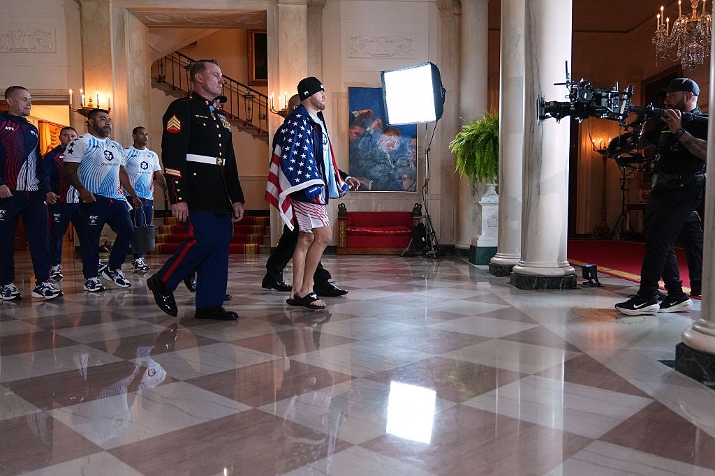 People, including a antheral draped successful an American flag, are being filmed arsenic they locomotion done an ornate room