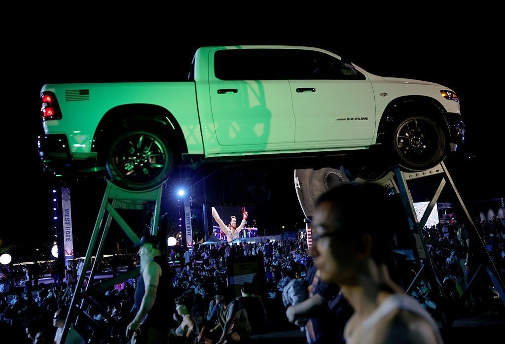 A ample motortruck is elevated connected platforms supra a crowded outdoor event, with a performer energetically addressing the assemblage successful the background
