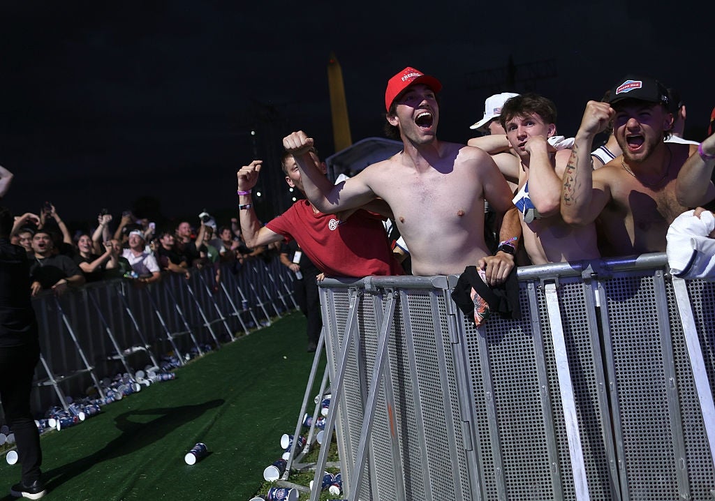 Group of excited fans cheering by a barricade astatine an outdoor event, immoderate with raised fists and caps