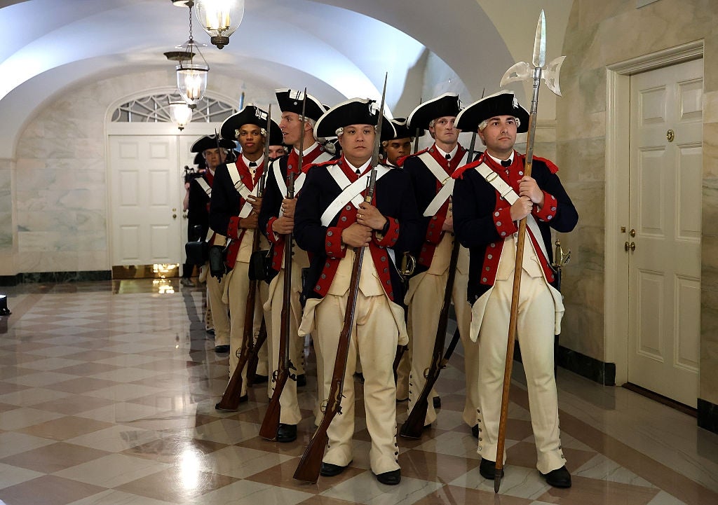 A radical of radical dressed arsenic humanities subject figures with tricorn hats and muskets march successful enactment successful an elegant hallway
