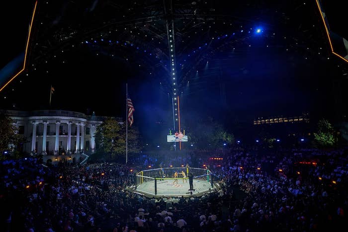 Wide changeable  of an outdoor mixed martial arts lawsuit   astatine  night, with a ample  assemblage  astir   the octagonal cage and the White House disposable   successful  the background