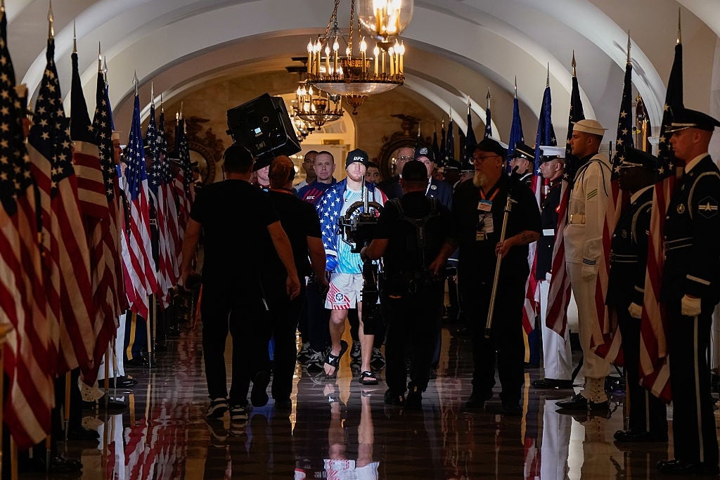 A radical of radical walks done a hallway lined with American flags. Some look to beryllium wearing uniforms, portion others person casual attire