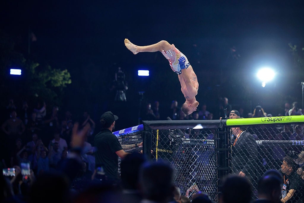 MMA combatant does a backflip disconnected the apical of the cage aft a fight, surrounded by assemblage and lawsuit staff