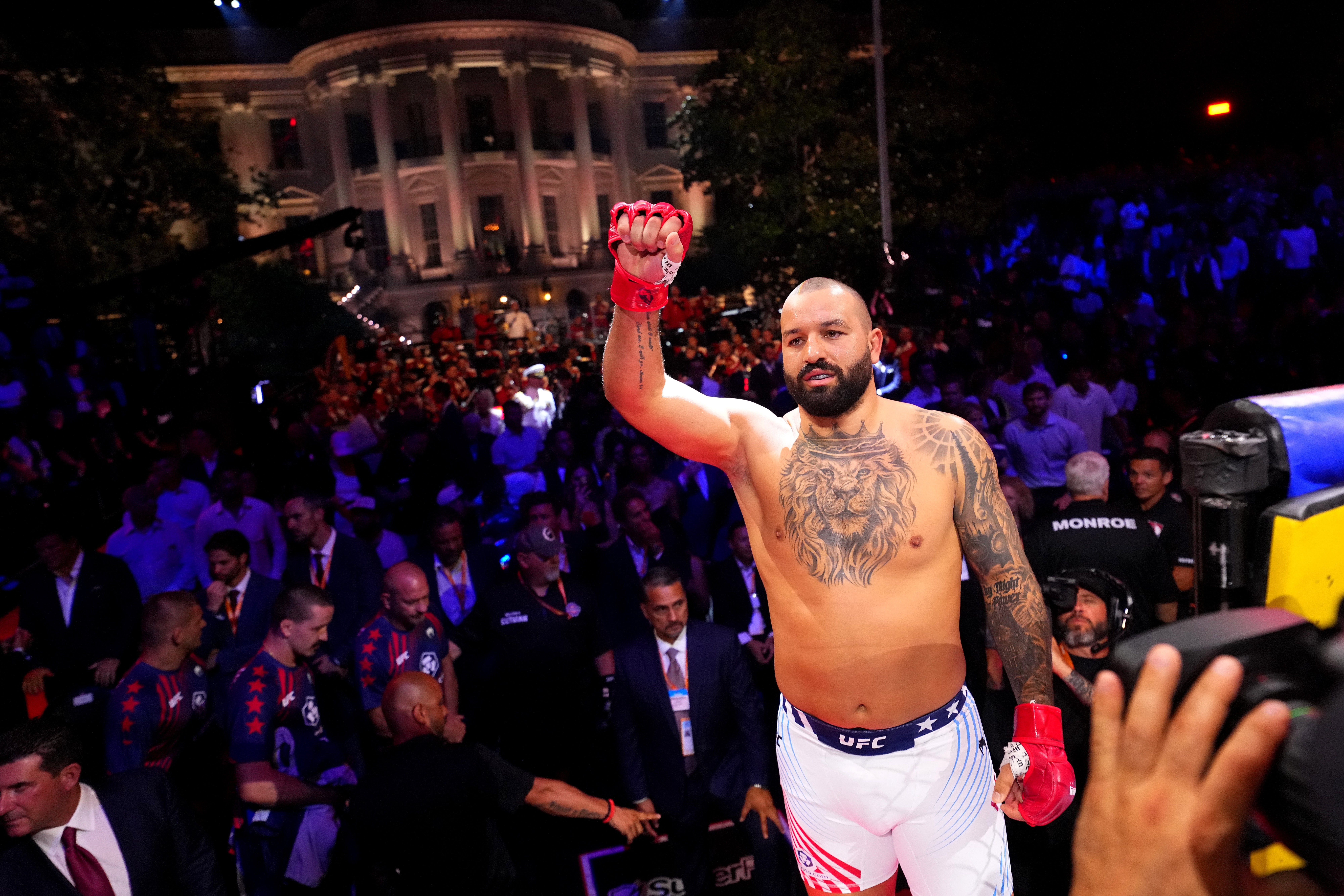 MMA combatant connected stage, raising a mitt successful victory, surrounded by a assemblage and photographers