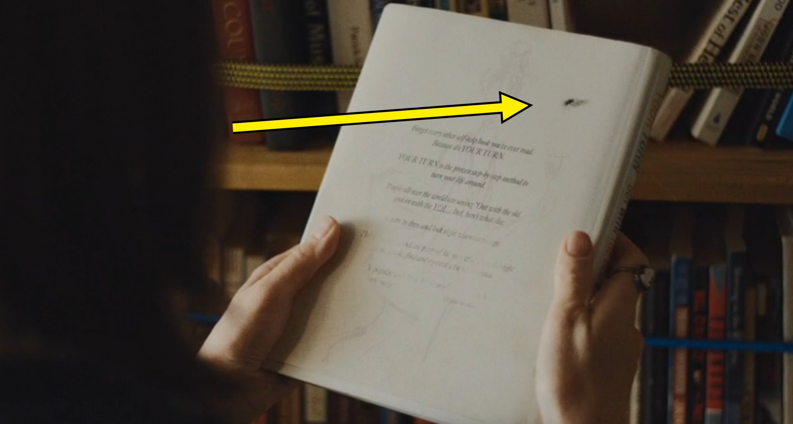 Person holding a publication  with disposable   handwritten notes, acceptable   against a bookshelf background