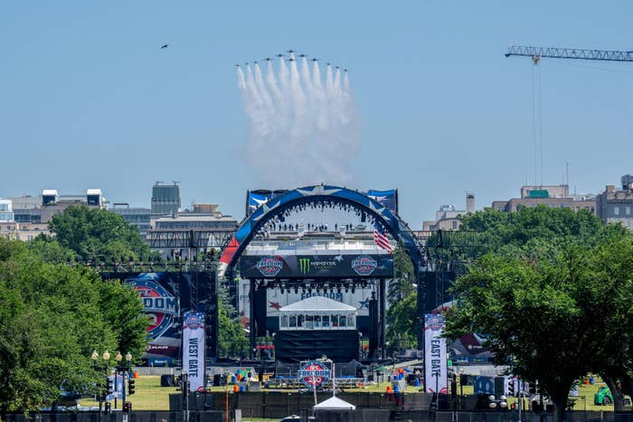 Outdoor festival signifier    with ample  arches, American flags, and subject   jets flying overhead, leaving trails successful  the sky
