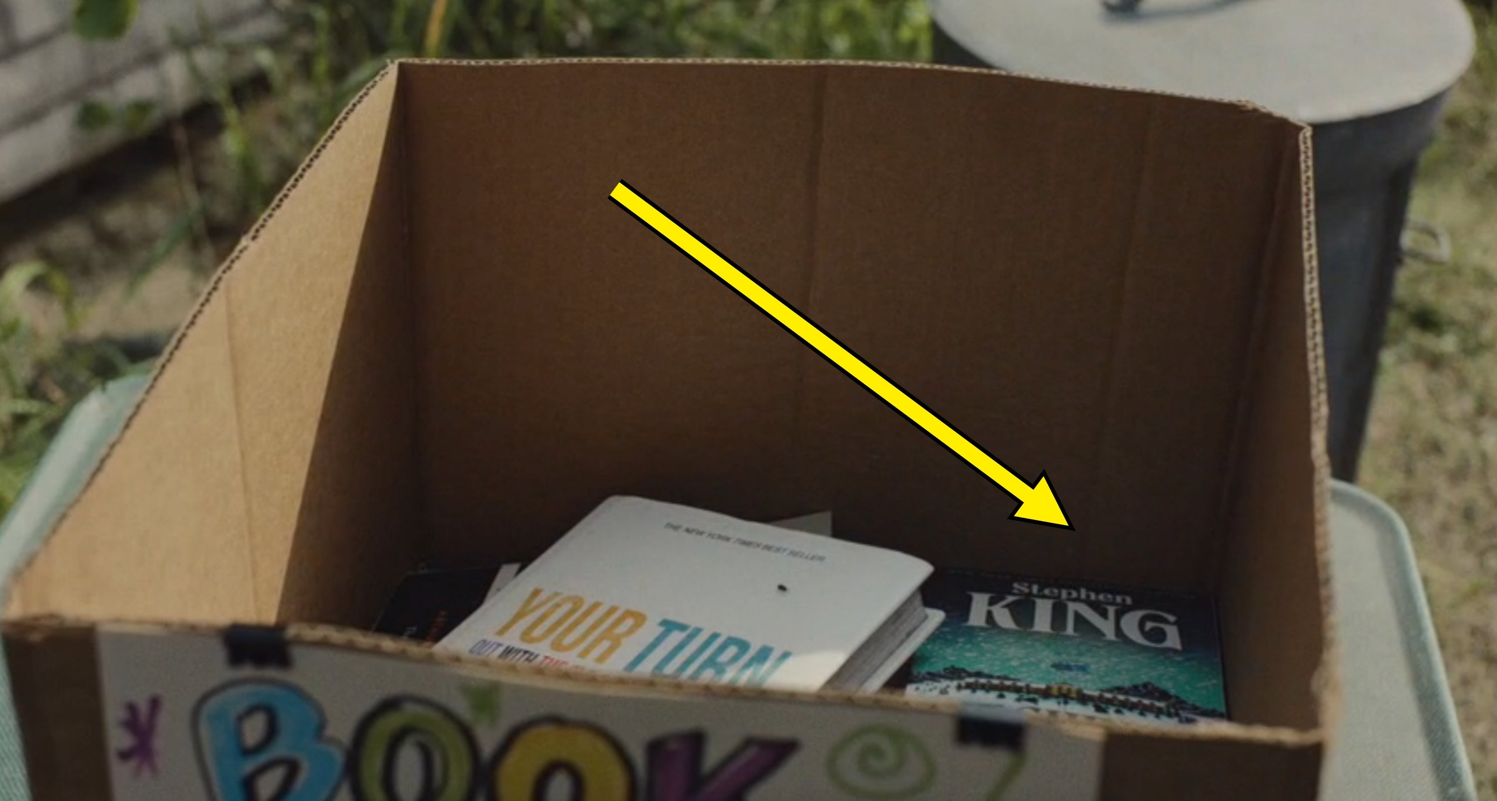 Box with books, including 1  titled "Your Turn" and a Stephen King novel, acceptable   outdoors