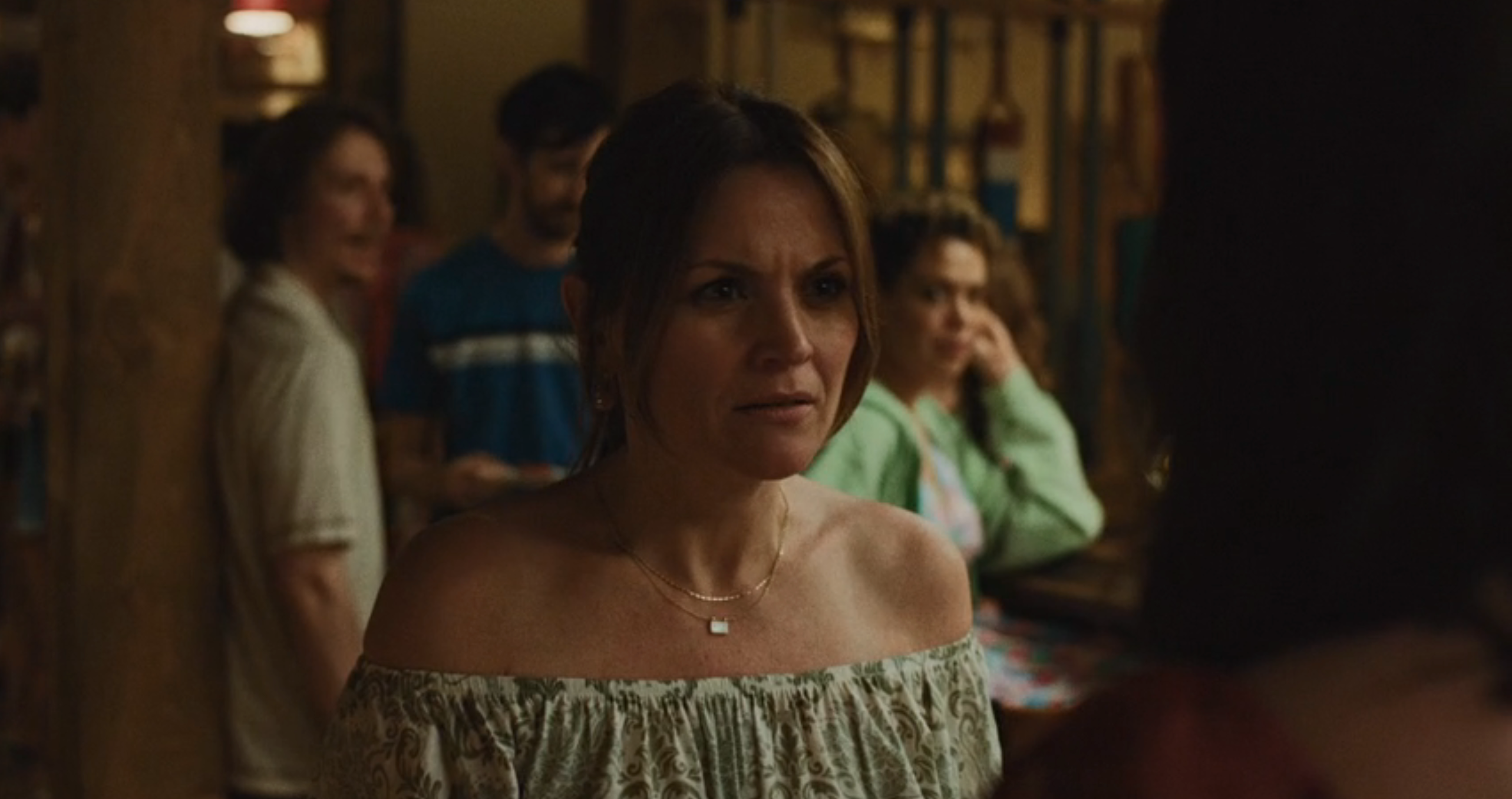 A pistillate   successful  an off-shoulder blouse looks acrophobic   successful  a radical  setting. Others are successful  the background, 1  with manus  connected  chin, suggesting a superior   discussion