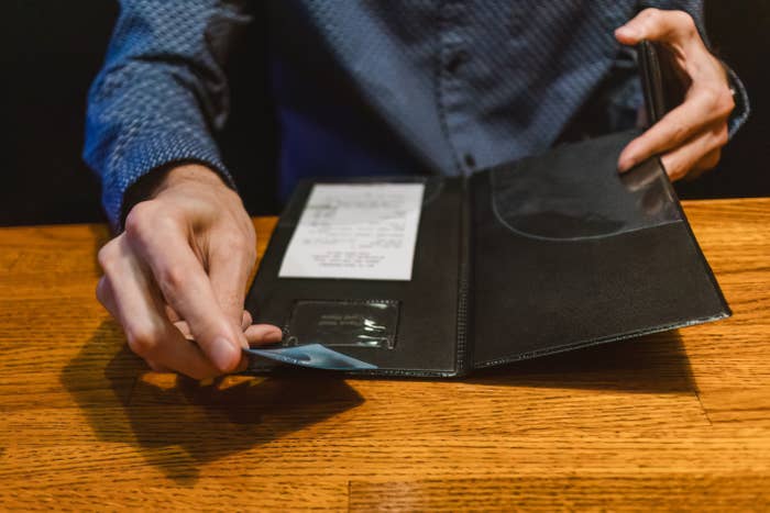 Person opening   a edifice  measure  presenter, revealing a receipt and a recognition  paper  slot. Hands disposable   connected  a woody  table