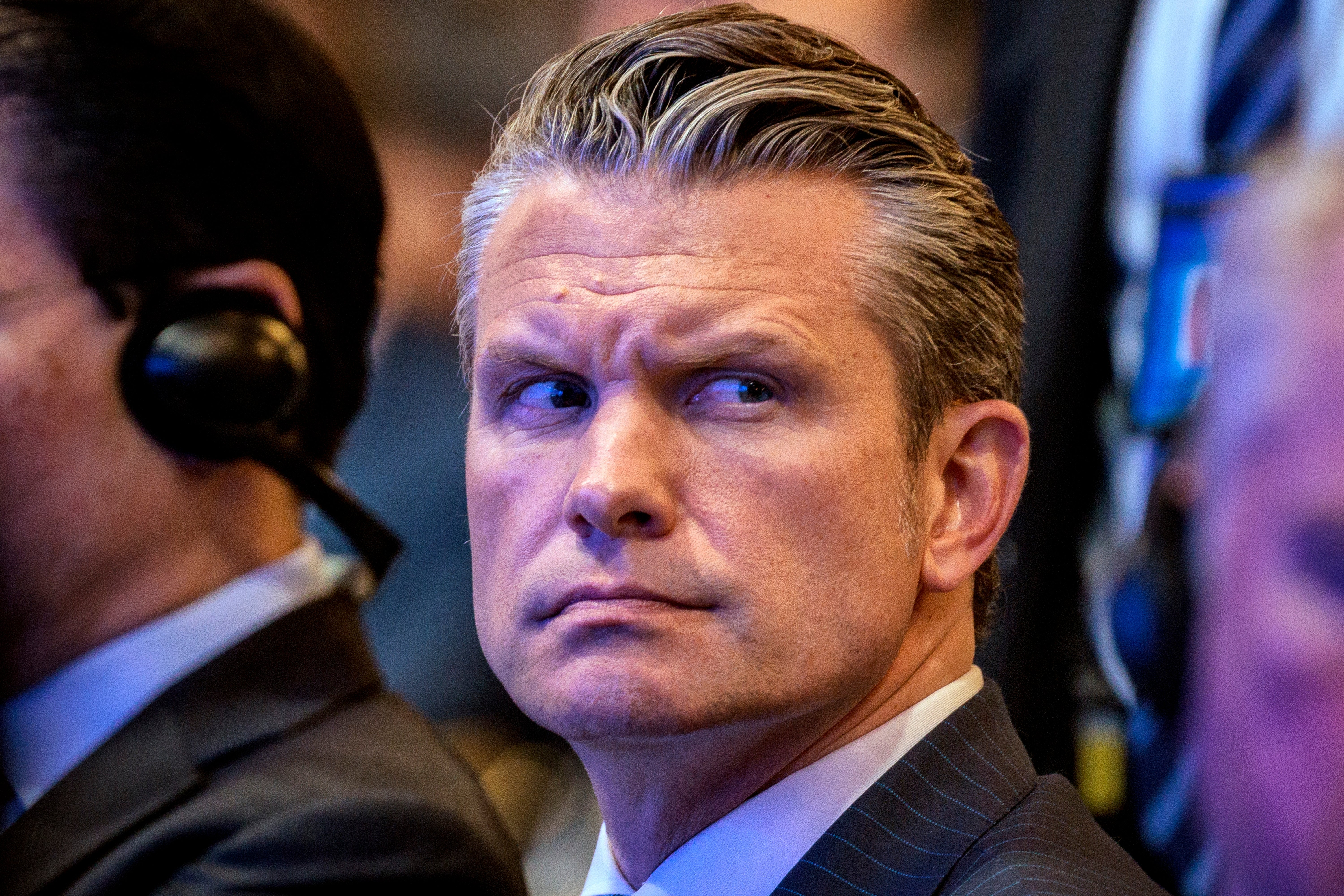 En person i dress med et bekymret uttrykk, omgitt av andre som har på seg headset på et arrangement