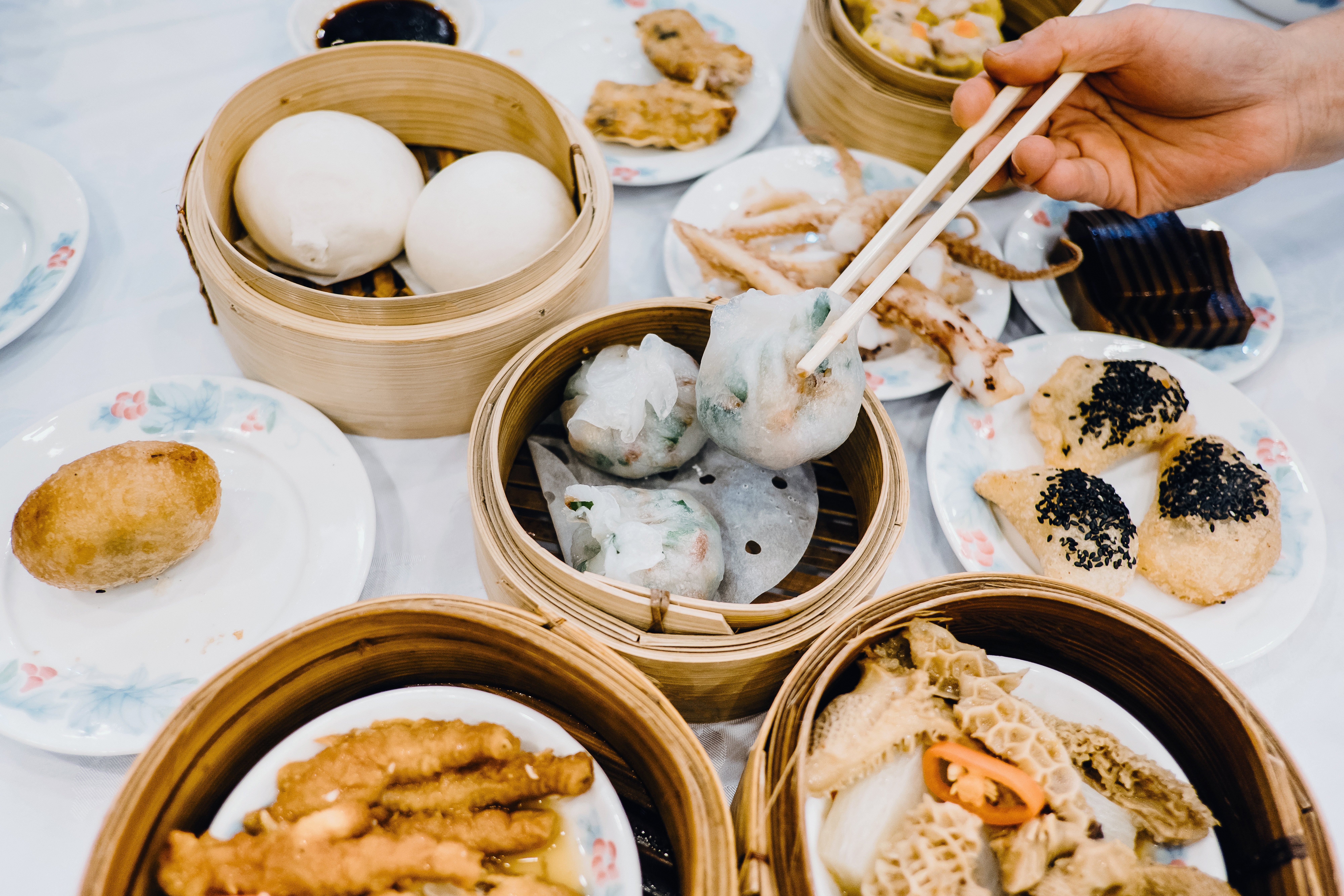 An assortment of dim sum dishes, including steamed buns, dumplings, and fried pastries, being served astatine a eating table