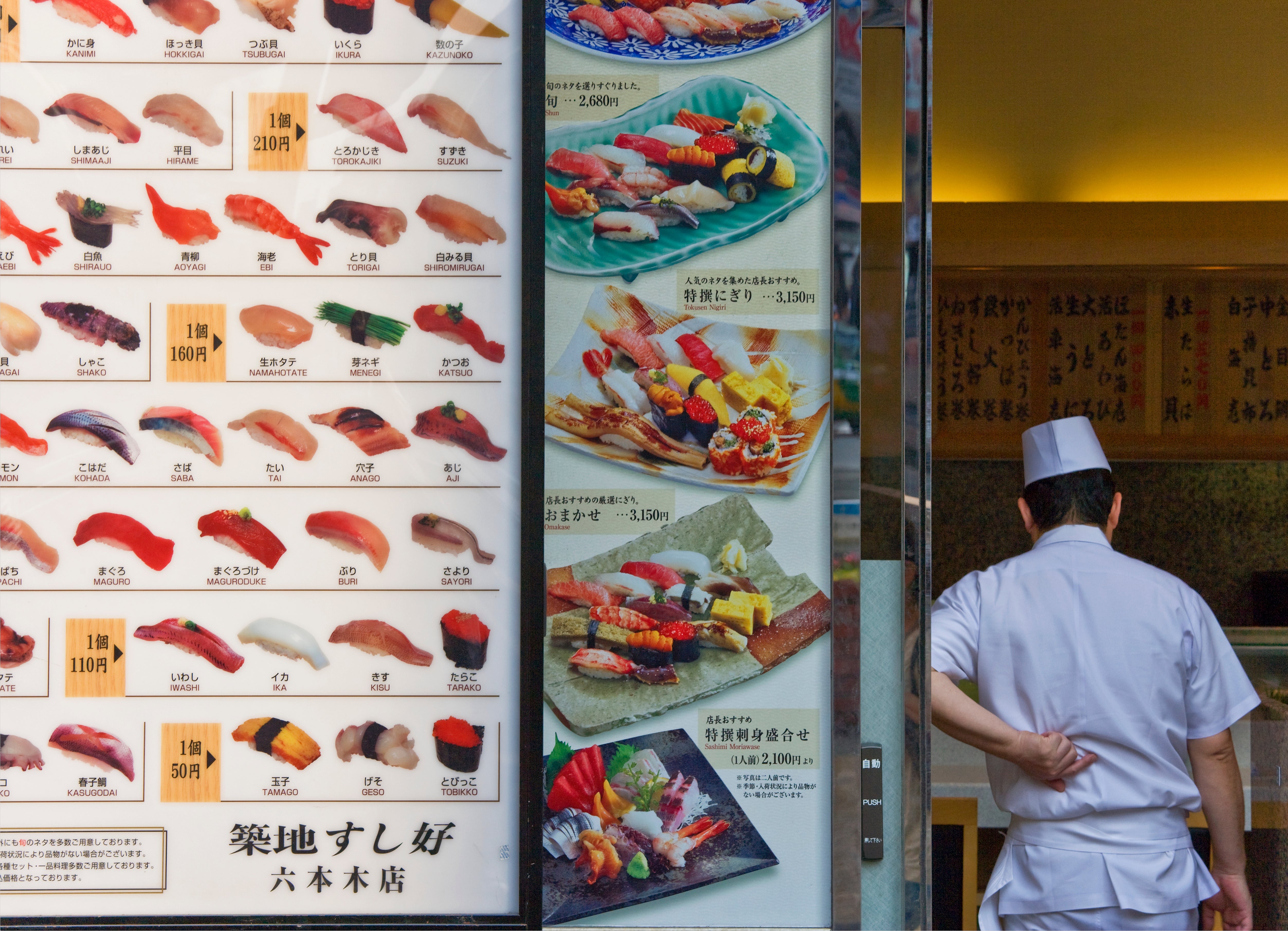 A sushi cook stands extracurricular a restaurant, adjacent to a paper displaying assorted sushi options and prices
