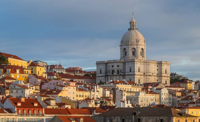 Scenic presumption    of Lisbon's Alfama territory  with the dome of the National Pantheon rising supra  colorful, historical  buildings nether  a cloudy sky