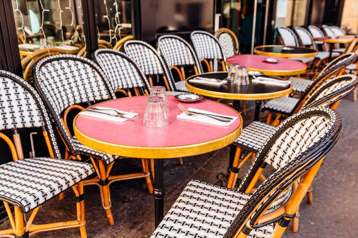 Outdoor café with patterned chairs and circular  tables acceptable   with glasses and napkins, creating a charming, inviting ambiance  for travelers