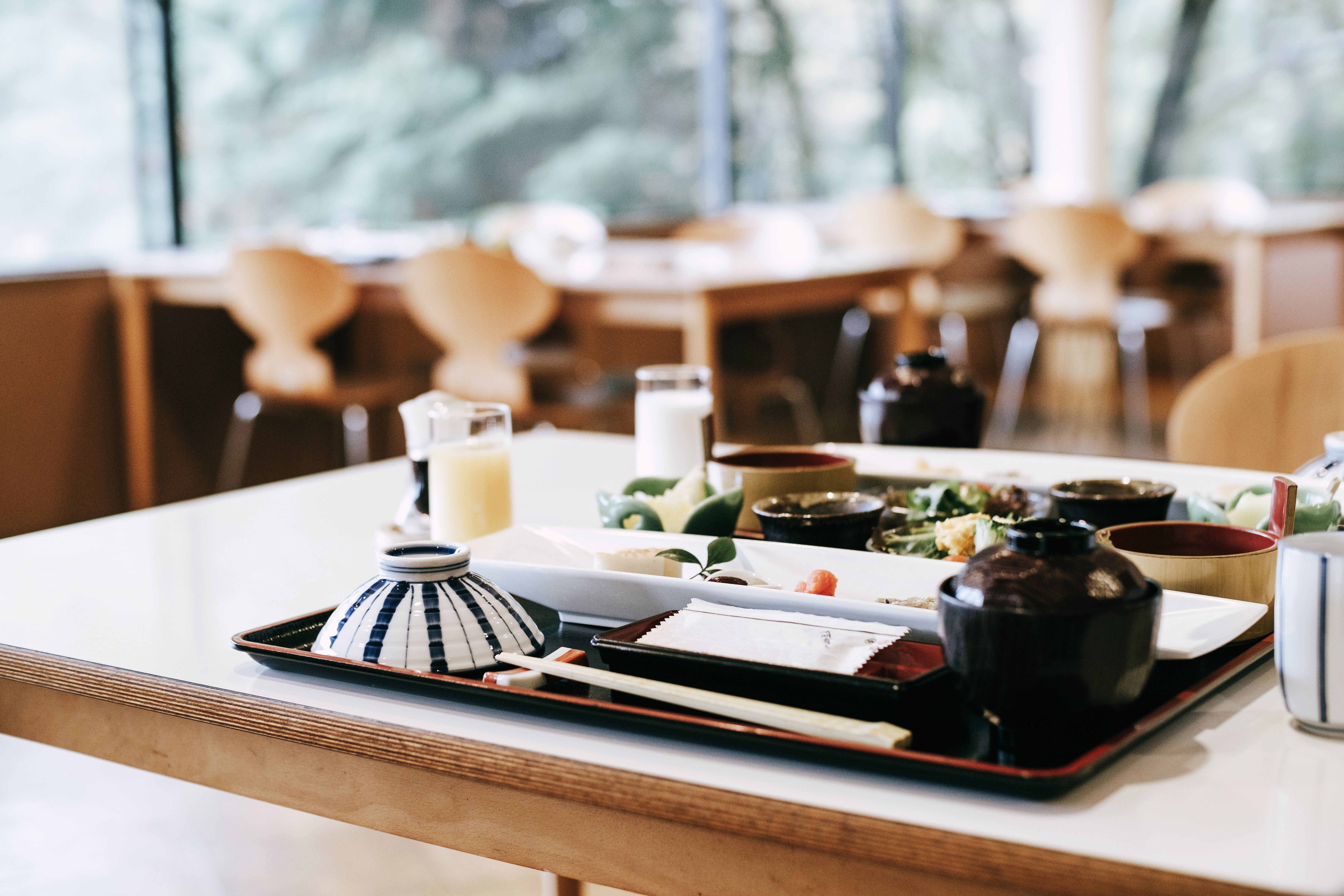 Japanese meal connected a array successful a agleam restaurant, featuring assorted dishes similar rice, pickled vegetables, and tea. Empty chairs are successful the background