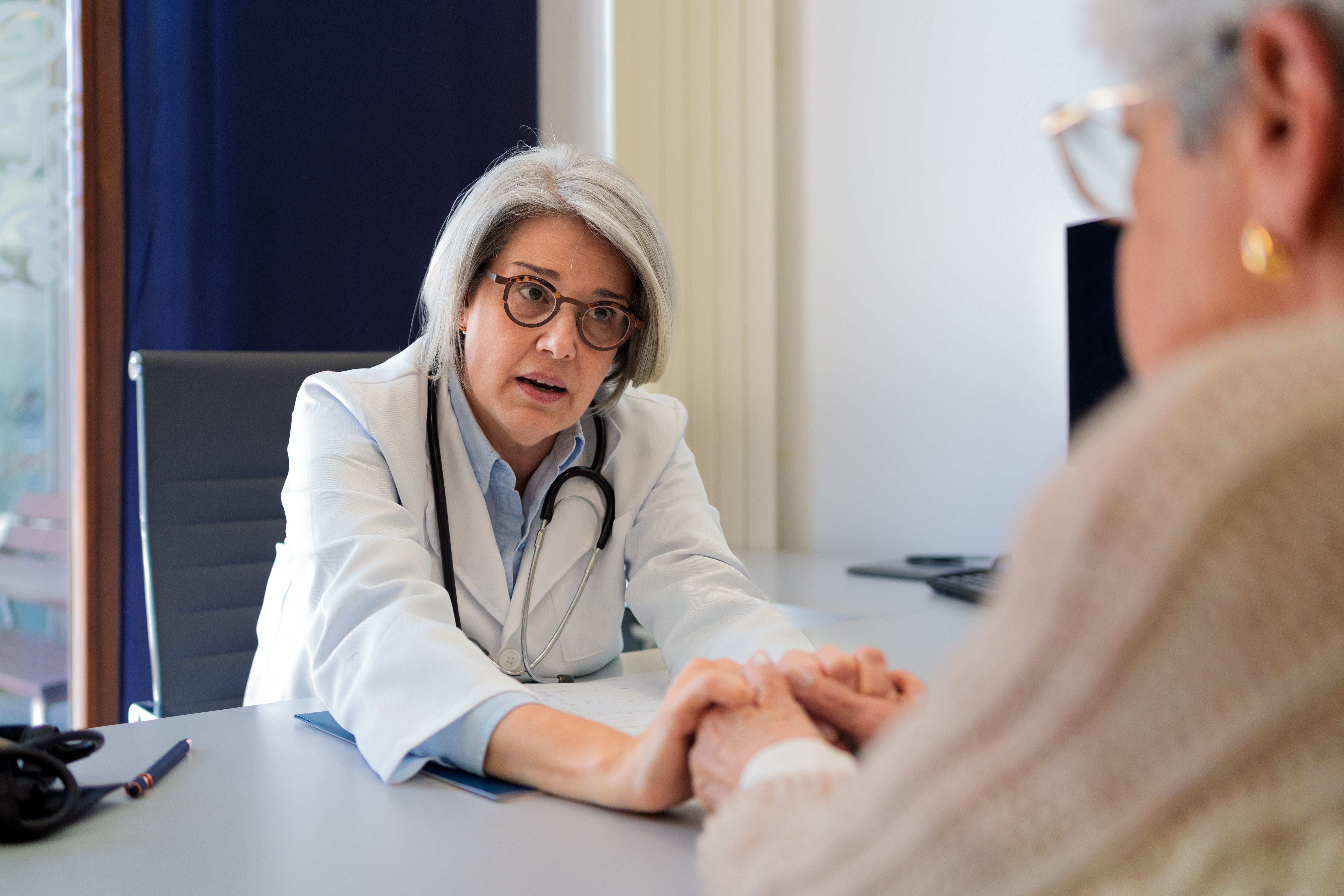 Doctor attentively listens to diligent portion holding their hands crossed a table successful a aesculapian office