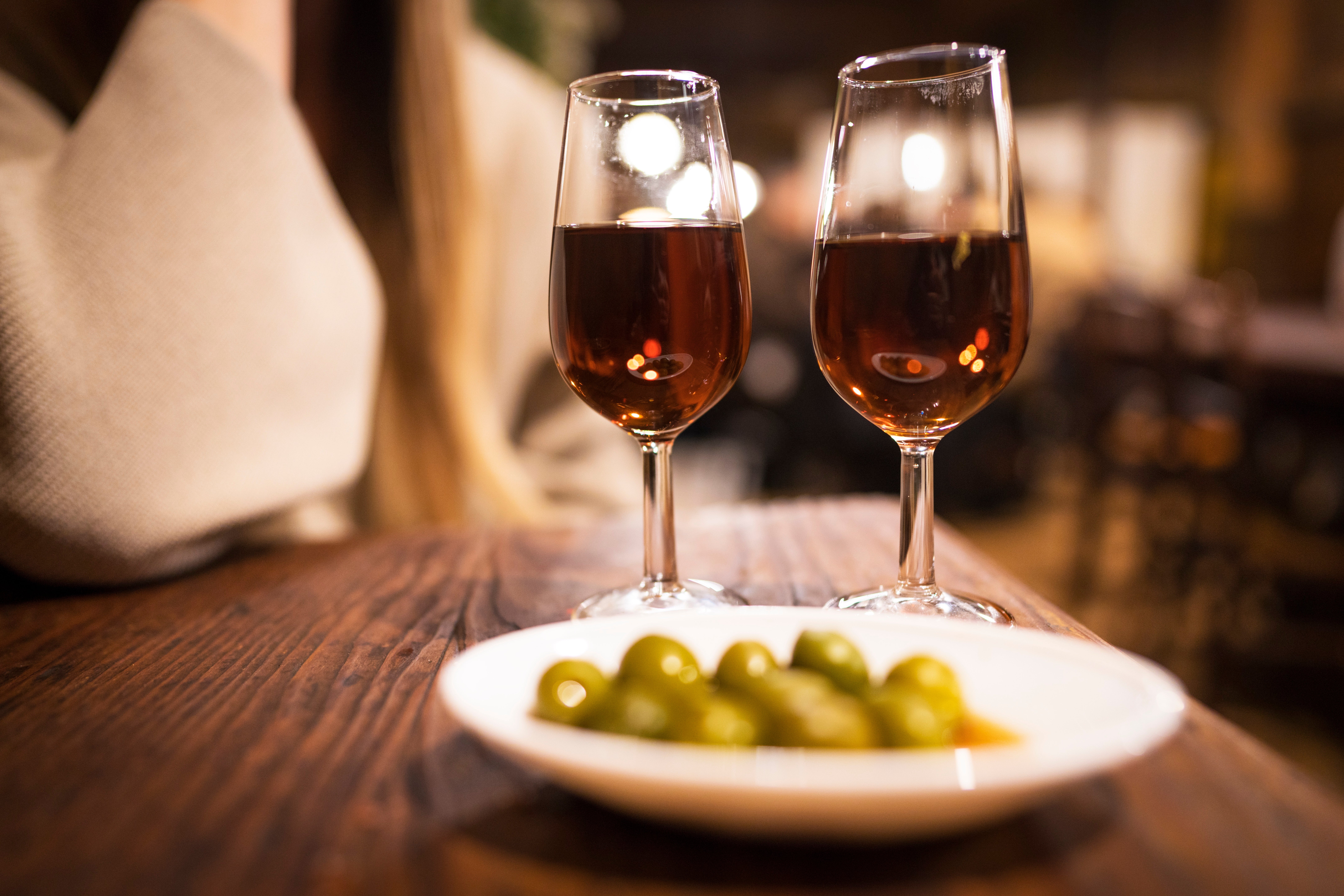 Two glasses of vino connected a woody array with a vessel of olives, acceptable successful a cozy eating environment