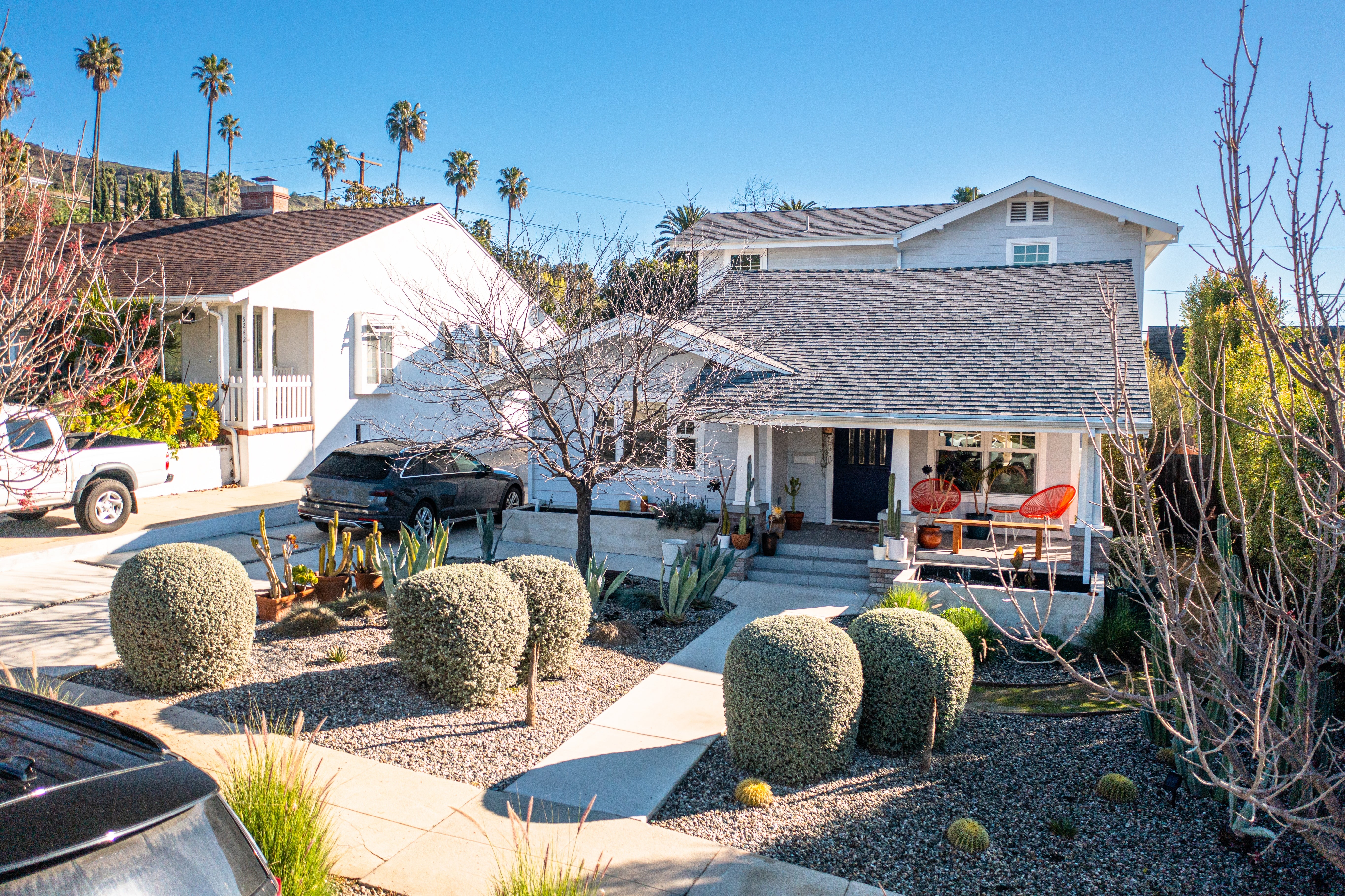 A sunny residential thoroughfare with small, neatly landscaped houses, featuring bushes and a fewer thenar trees successful the background