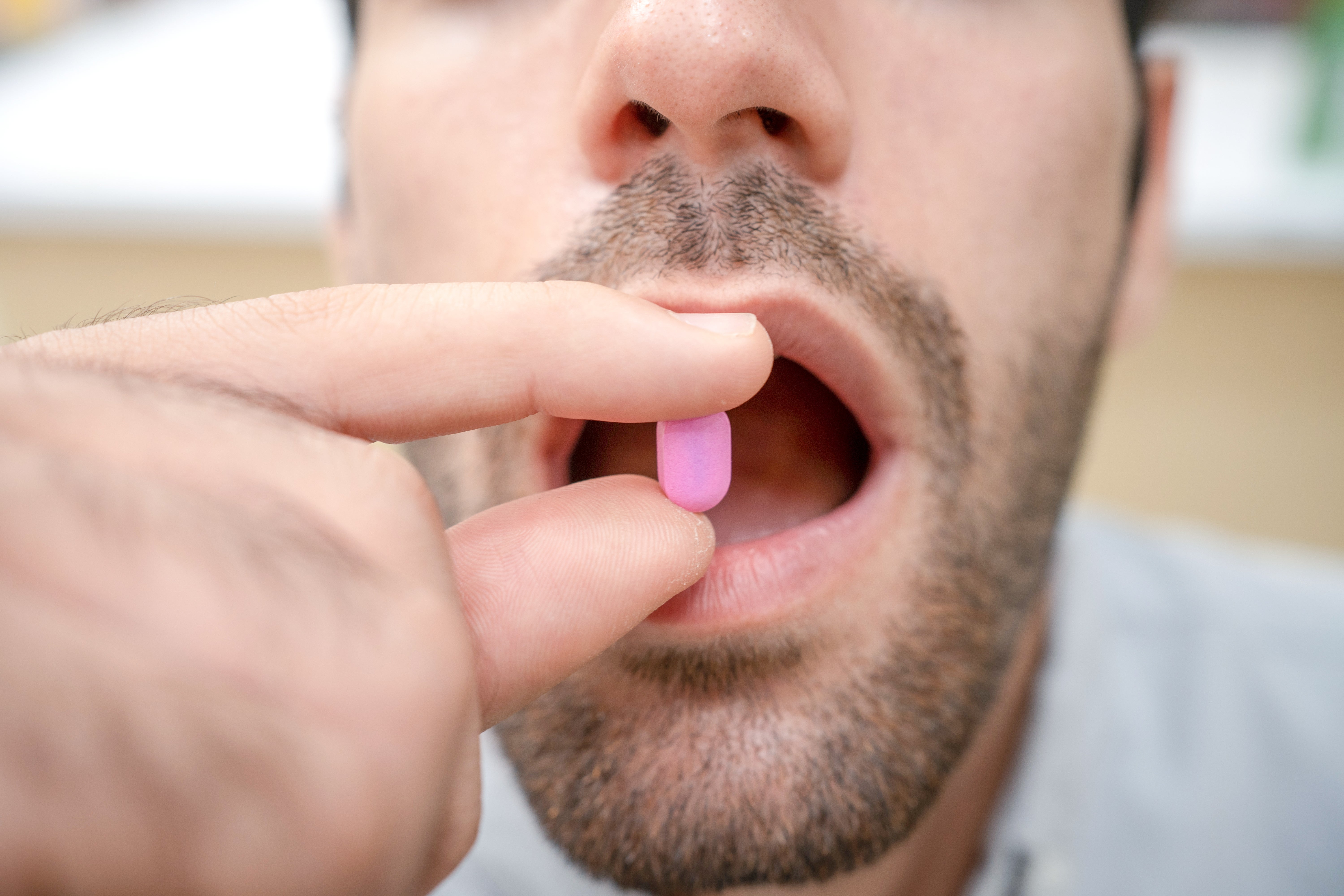 A idiosyncratic takes a pill, holding it betwixt their fingers and bringing it adjacent to their unfastened mouth