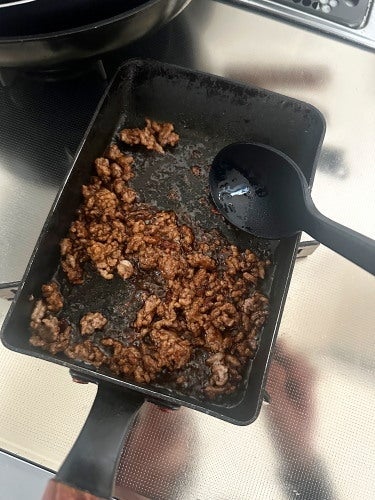 炒めたひき肉が入ったフライパンと横に置かれたスプーン。