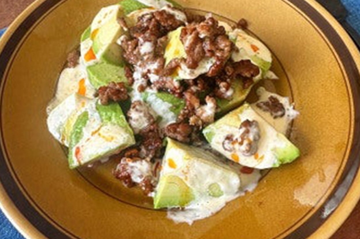 アボカドと牛ひき肉がトッピングされた料理が皿に盛られている。背景に青いナプキンが見える。