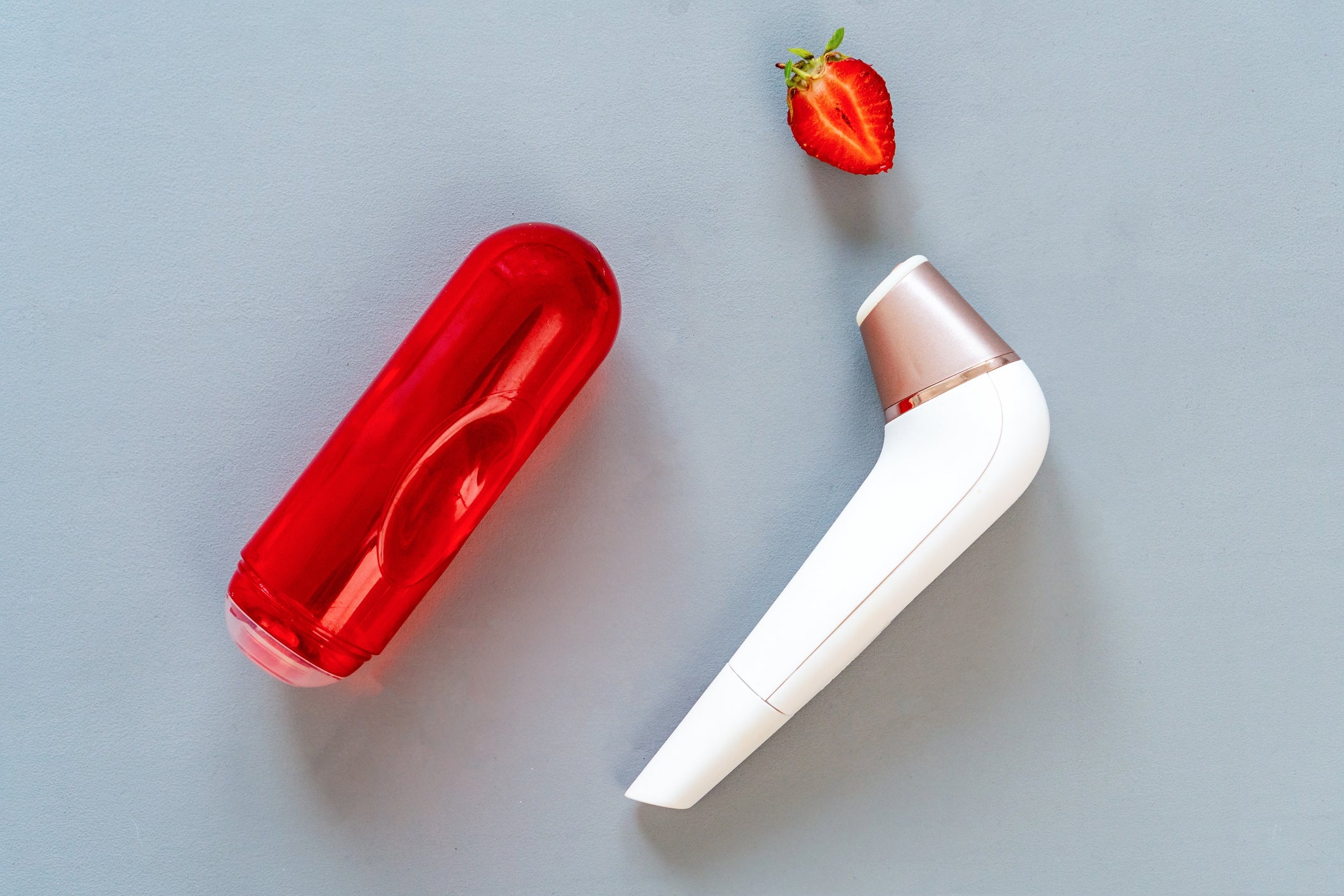Red case, a achromatic instrumentality with a golden accent, and a sliced strawberry connected a grey surface. The representation focuses connected idiosyncratic attraction oregon quality tools