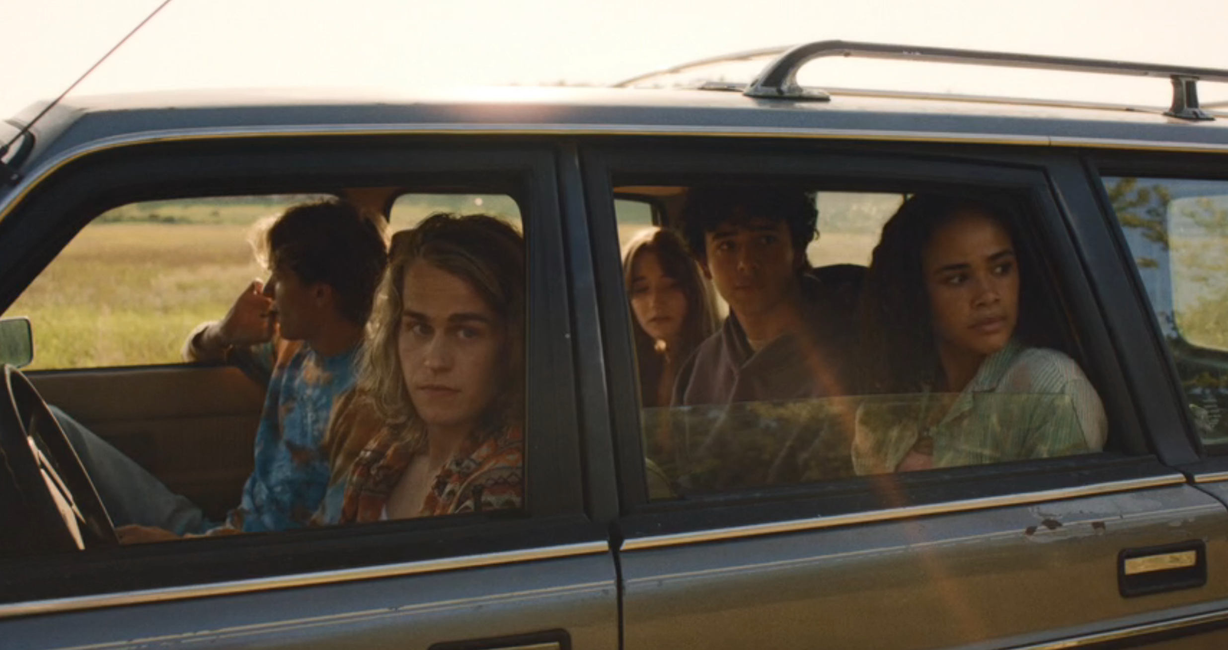 A radical  of young adults sitting successful  a car, looking retired  the windows with varied expressions