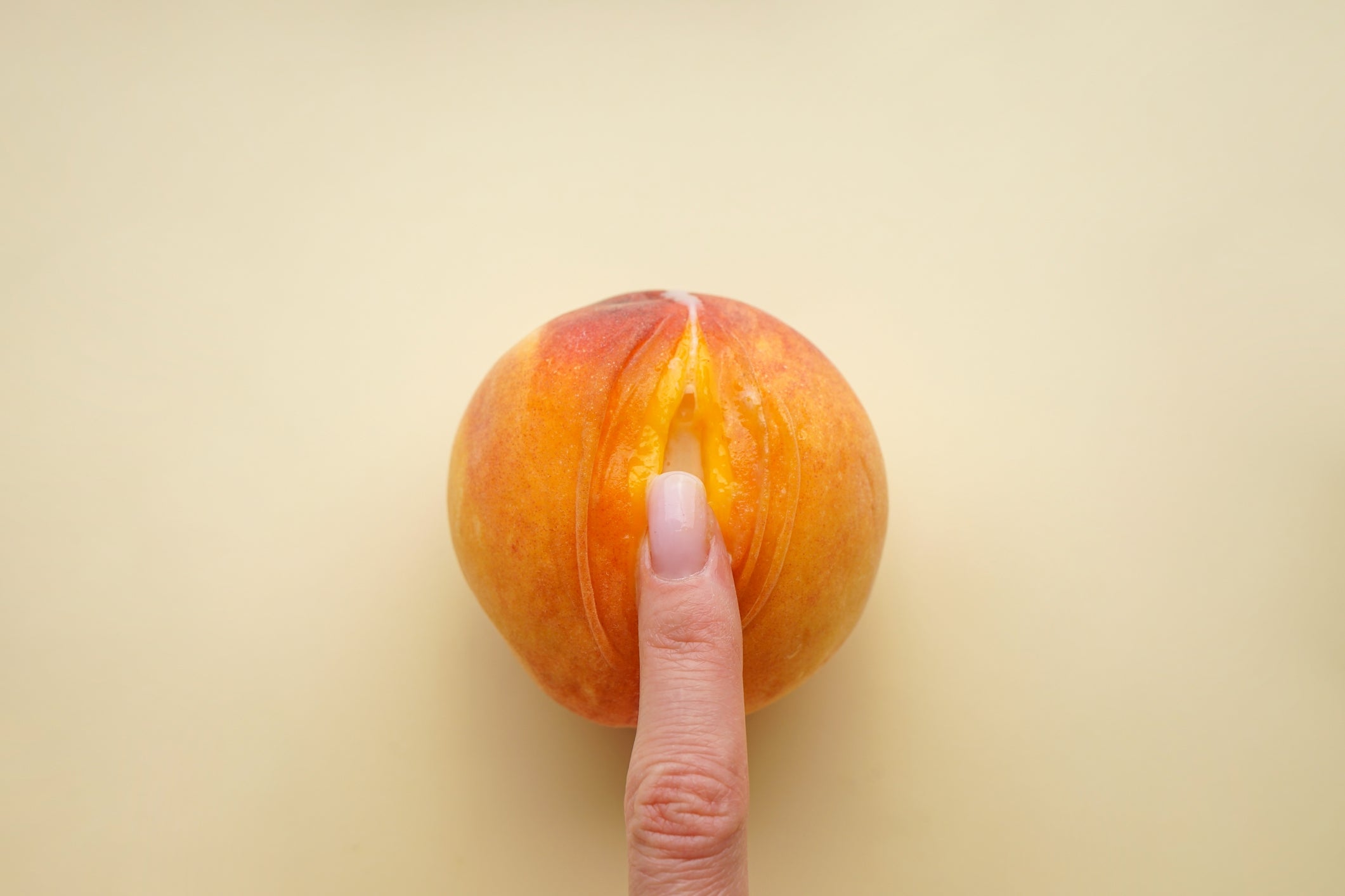 Finger touching a peach, symbolizing wellness and wellness themes