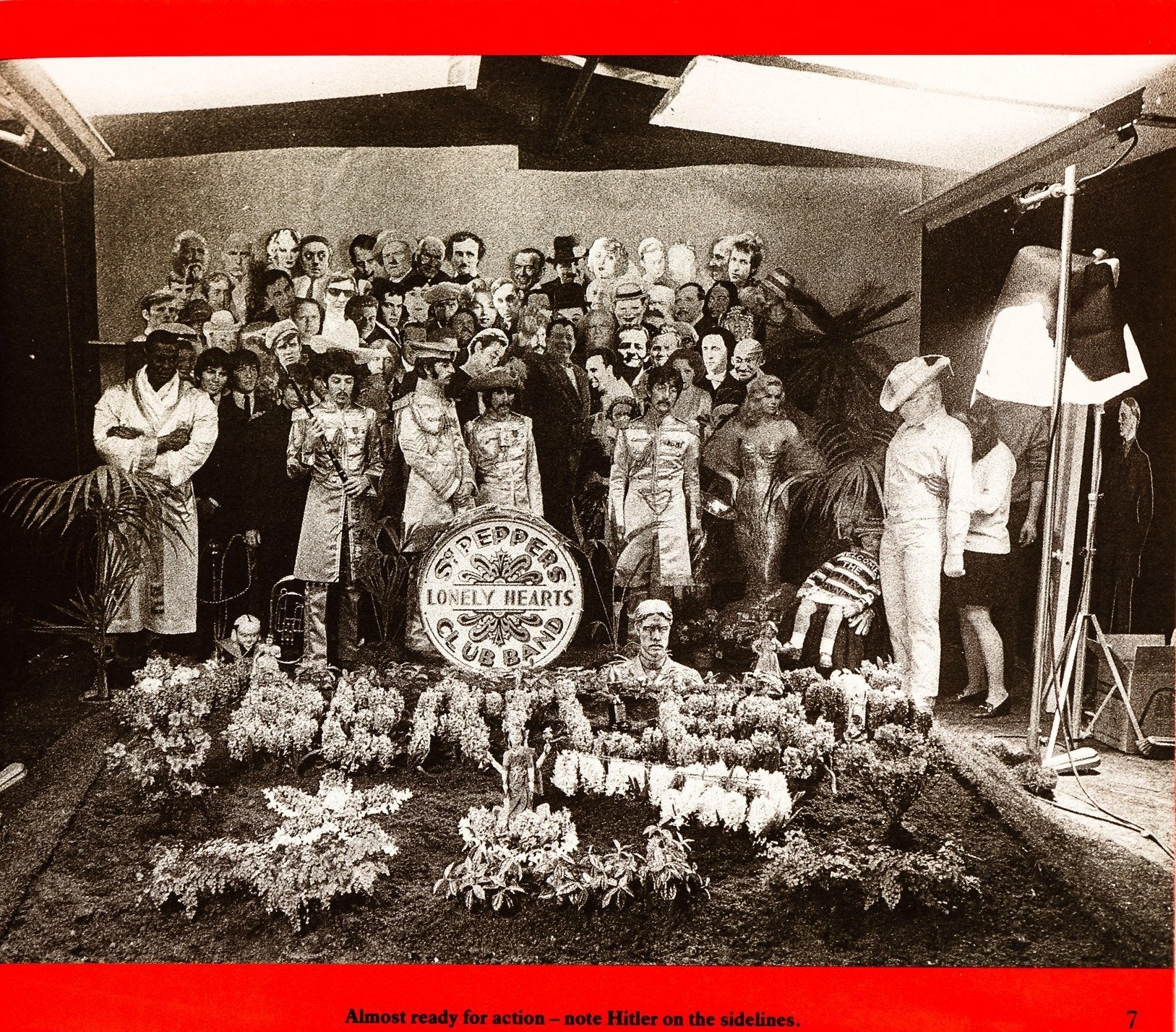 A radical  of people, immoderate   successful  costumes resembling humanities  figures, are gathered astir   a "Lonely Hearts" motion   successful  a staged plot  setting