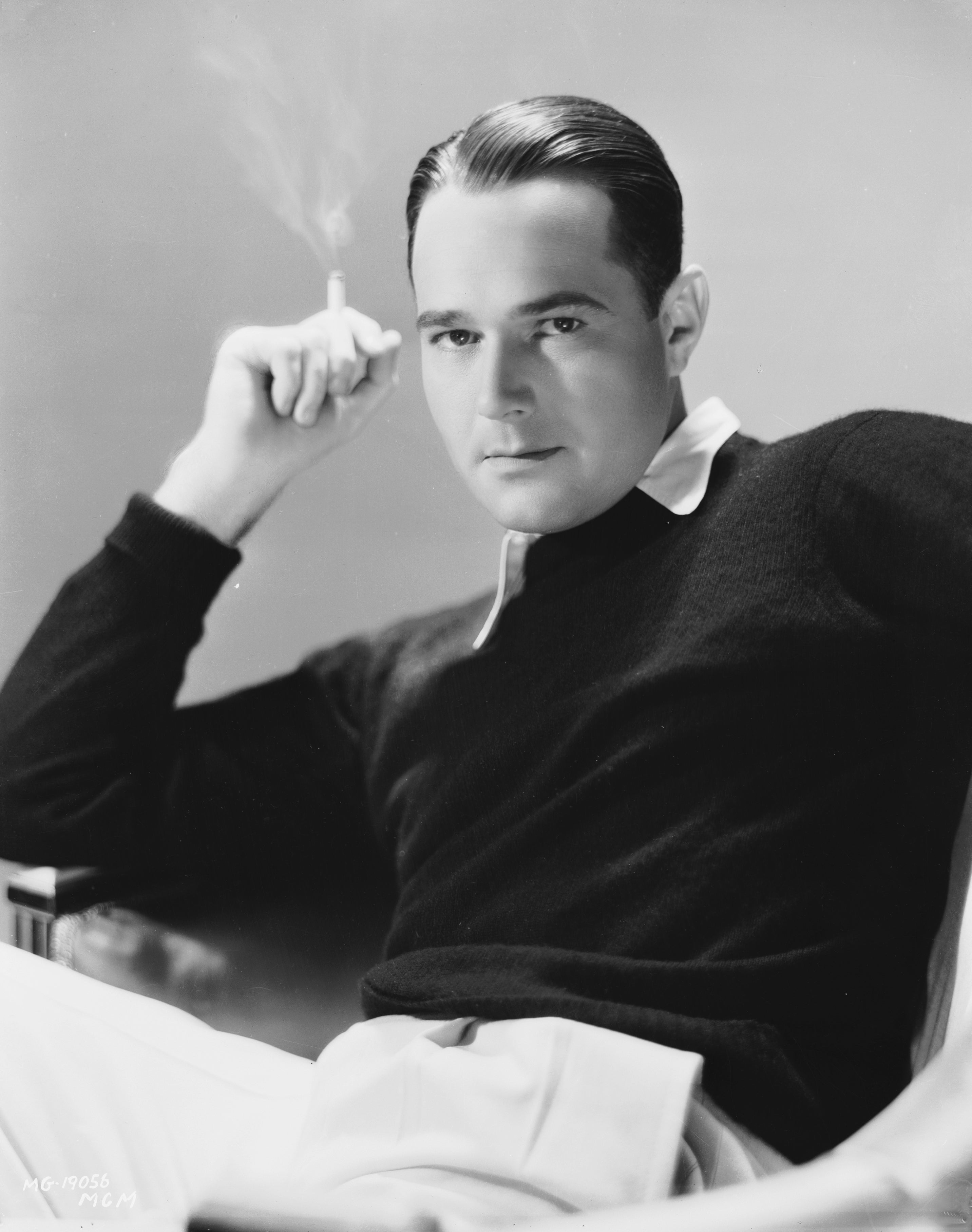 Classic representation    of a idiosyncratic   from the aboriginal  20th century, seated, holding a cigaret  with a thoughtful expression, wearing a sweater implicit    a collared shirt