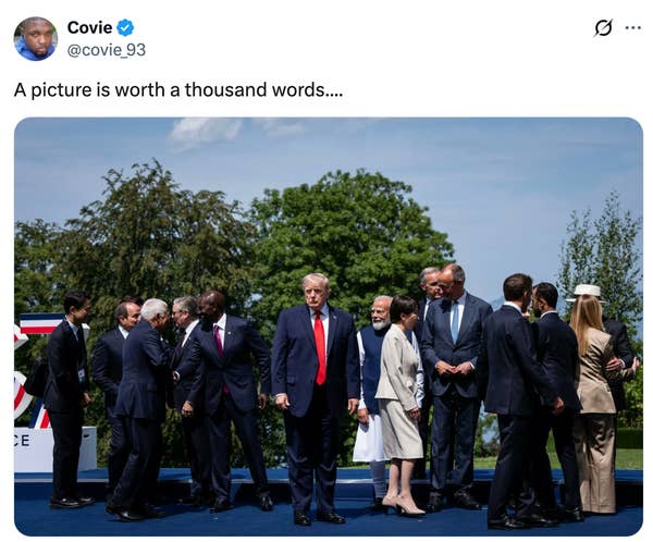 Group of world leaders in formal attire standing and interacting outdoors, with one standing prominently apart from the group