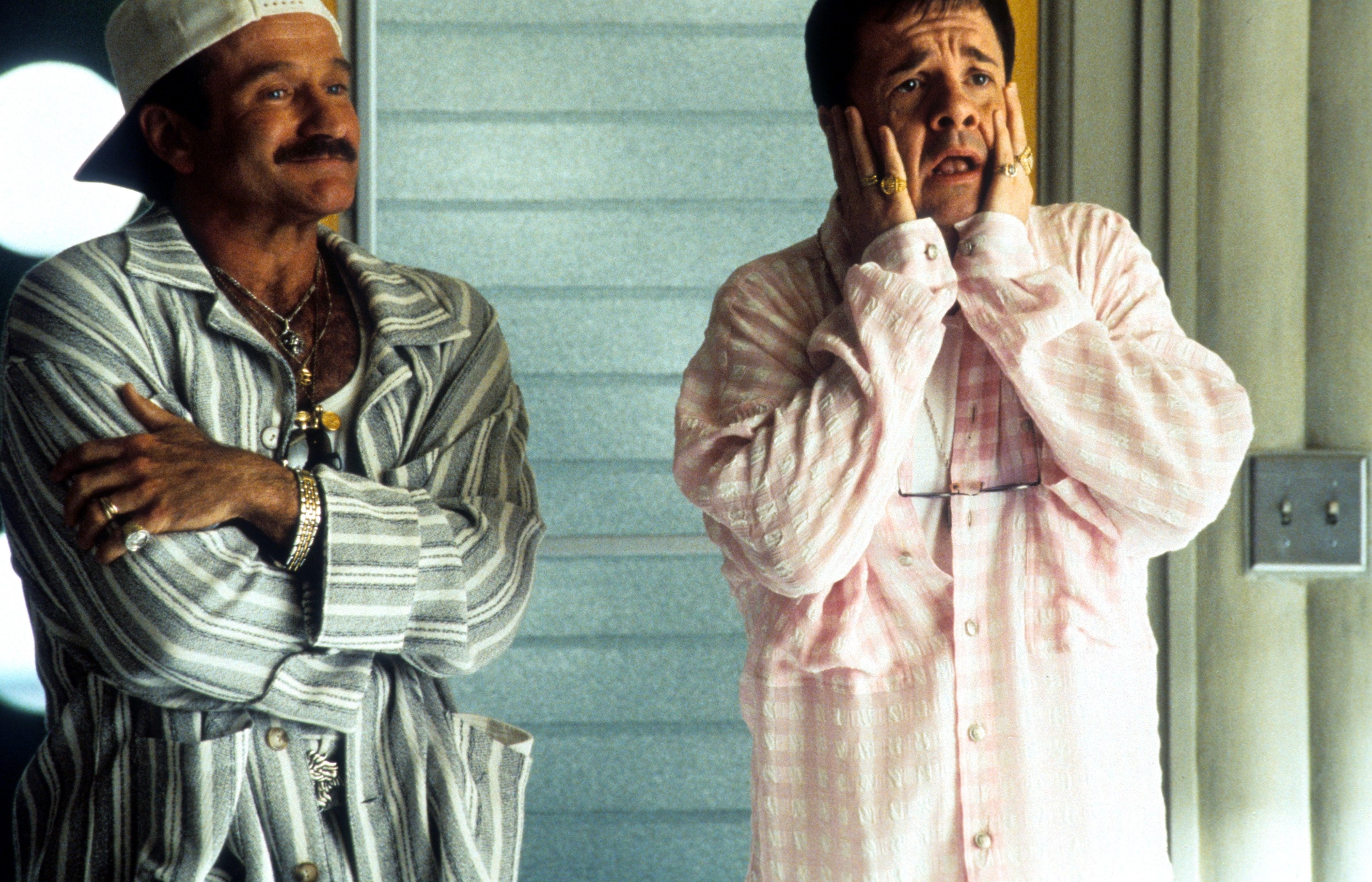 Two individuals successful  casual, patterned shirts basal   indoors, 1  with hands connected  face, expressing surprise