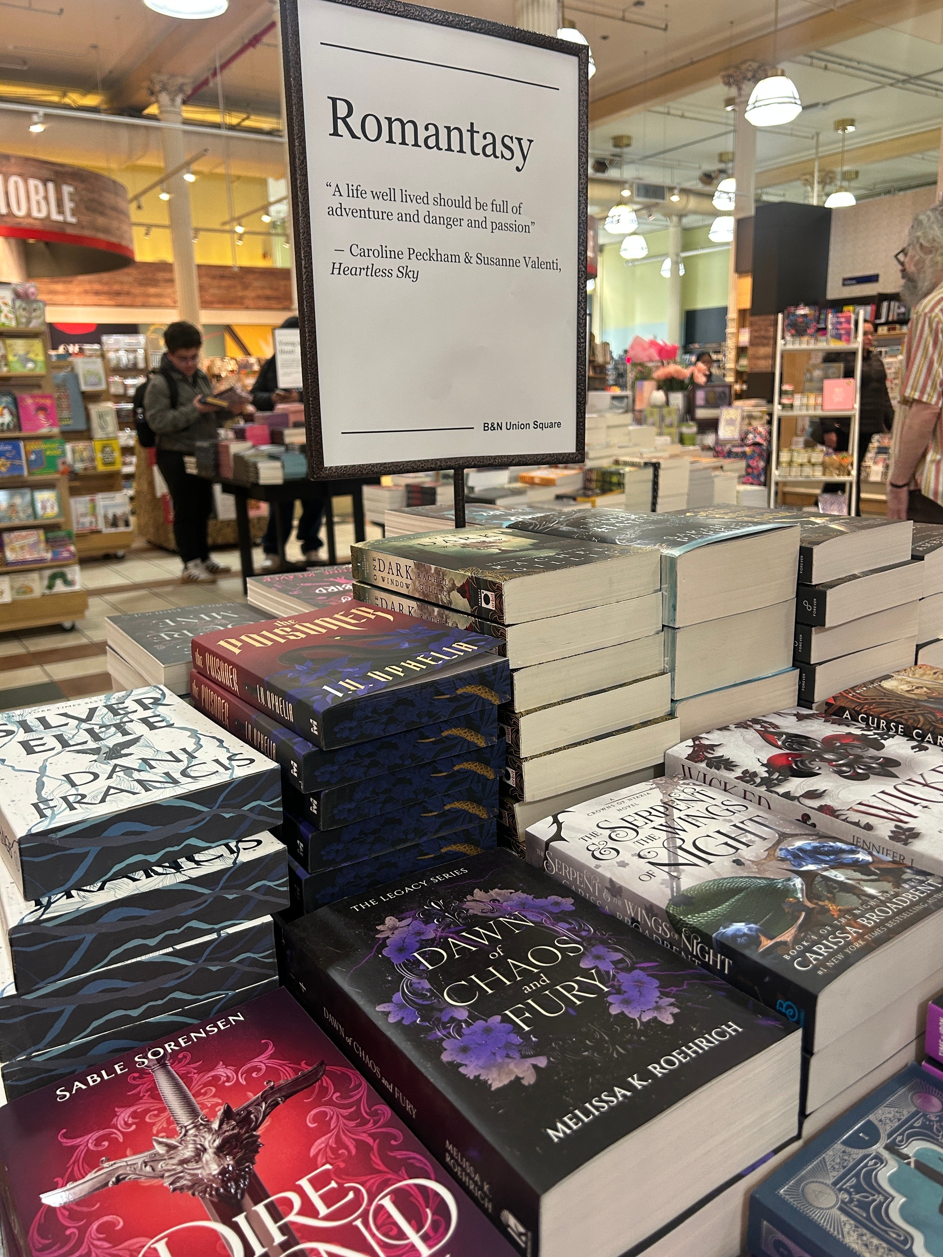 Bookstore show with phantasy romance novels. A motion reads a punctuation astir escapade and passionateness by Caroline Peckham and Susanne Valenti