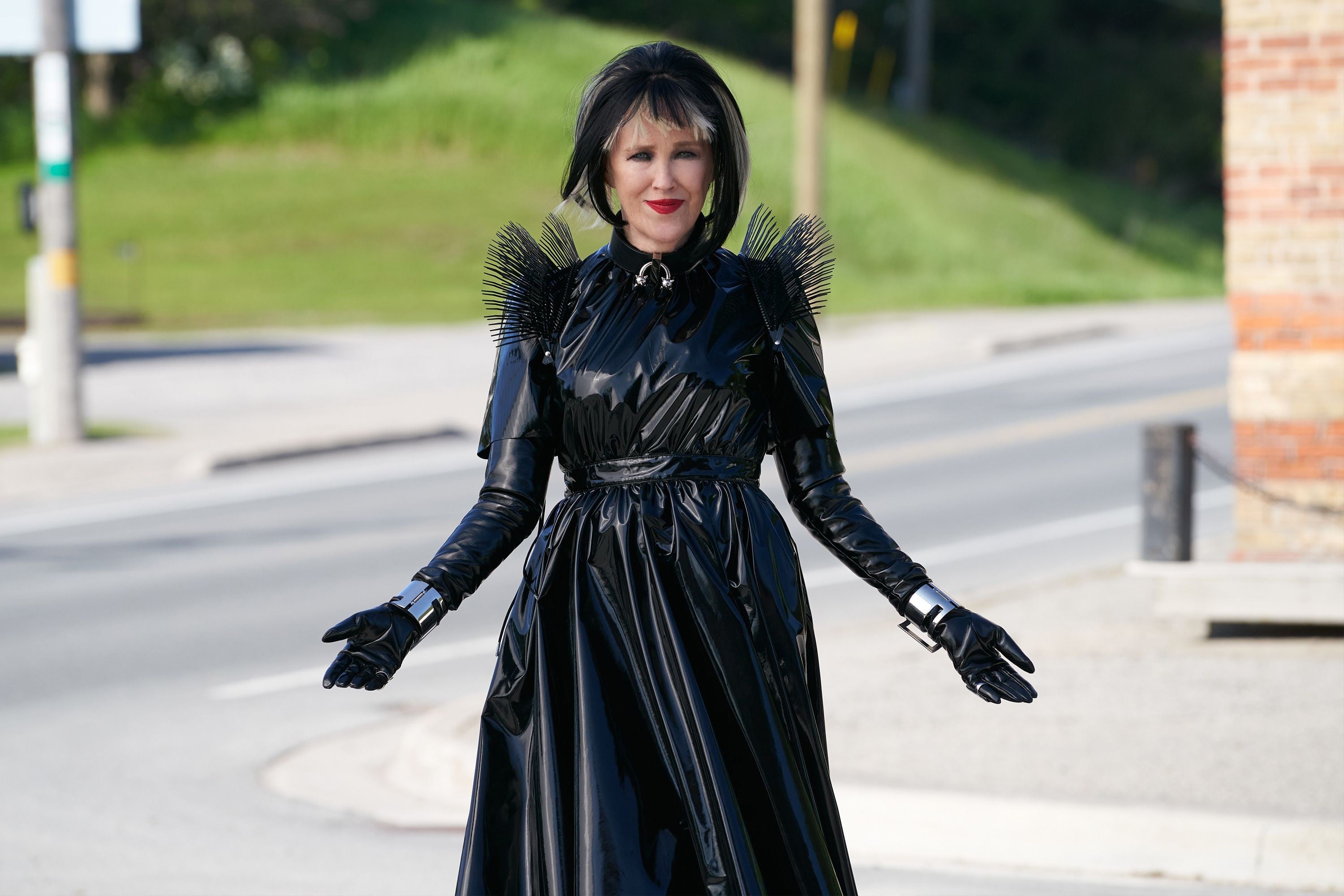 Person successful  a dramatic, glossy achromatic  formal  with spiked enarthrosis  details stands connected  a street, appearing stylish and confident