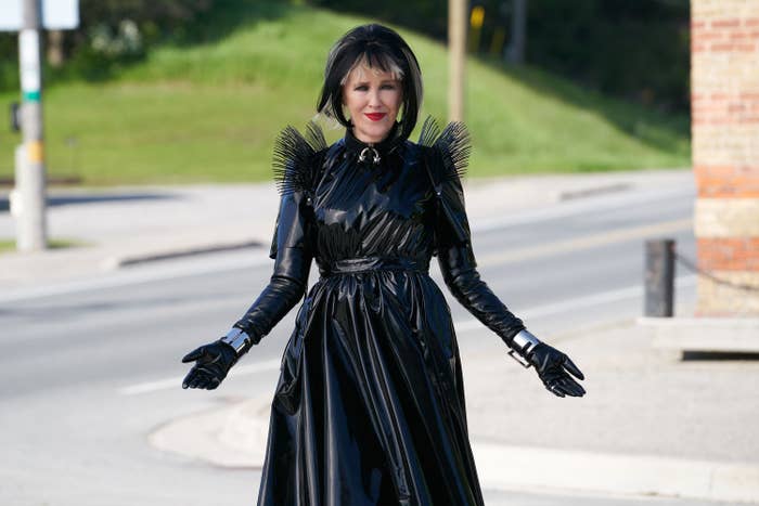 Person successful  a dramatic, glossy achromatic  formal  with spiked enarthrosis  details stands connected  a street, appearing stylish and confident