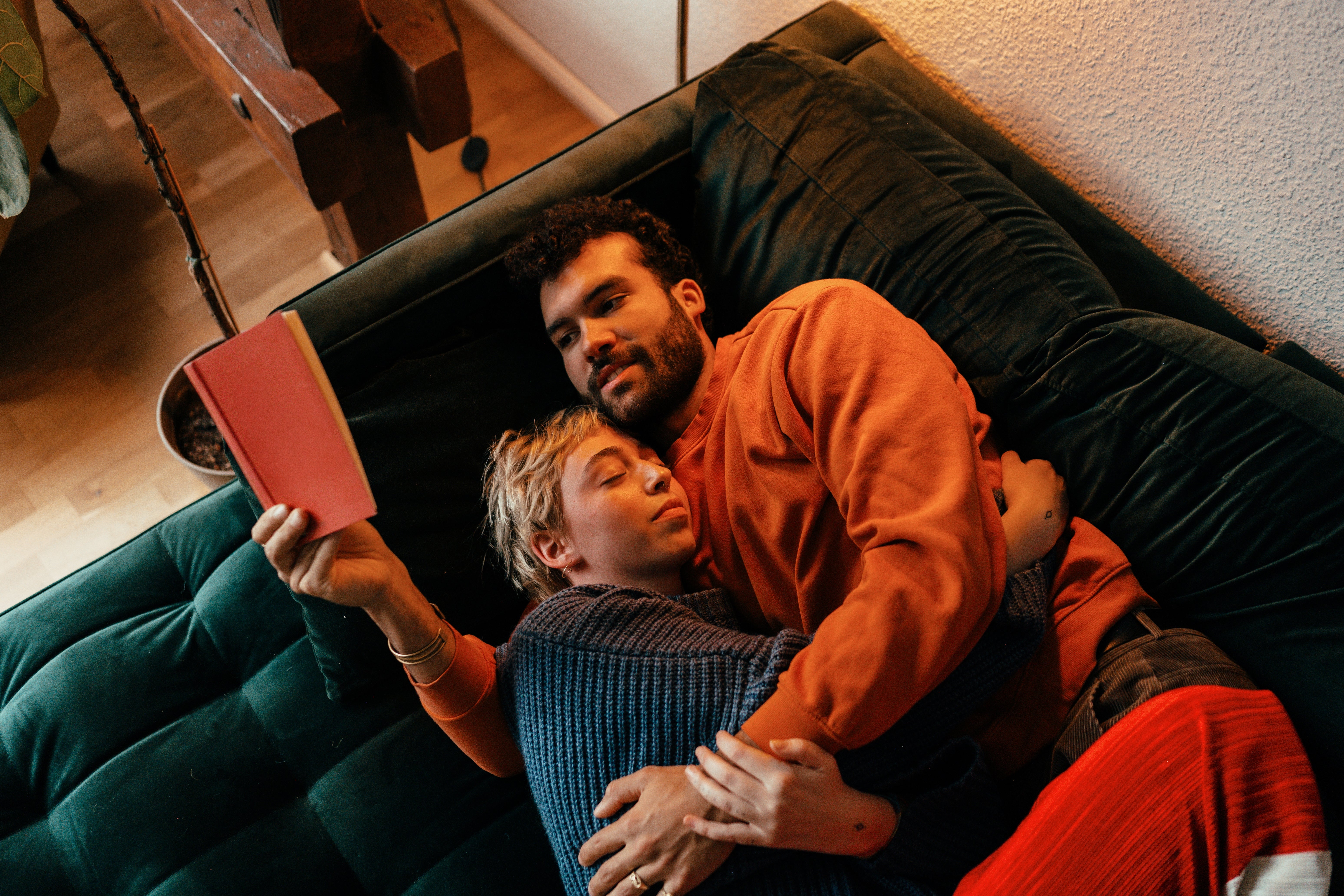 A mates cuddles connected a sofa, 1 speechmaking a book. They look relaxed and content, showcasing intimacy and affection