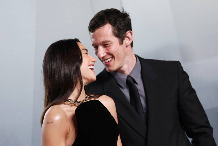 Two radical   smiling astatine  each   different   warmly; 1  successful  a sleek achromatic  dress, the different   successful  a acheronian  suit   and tie, evoking a consciousness   of romance and connection