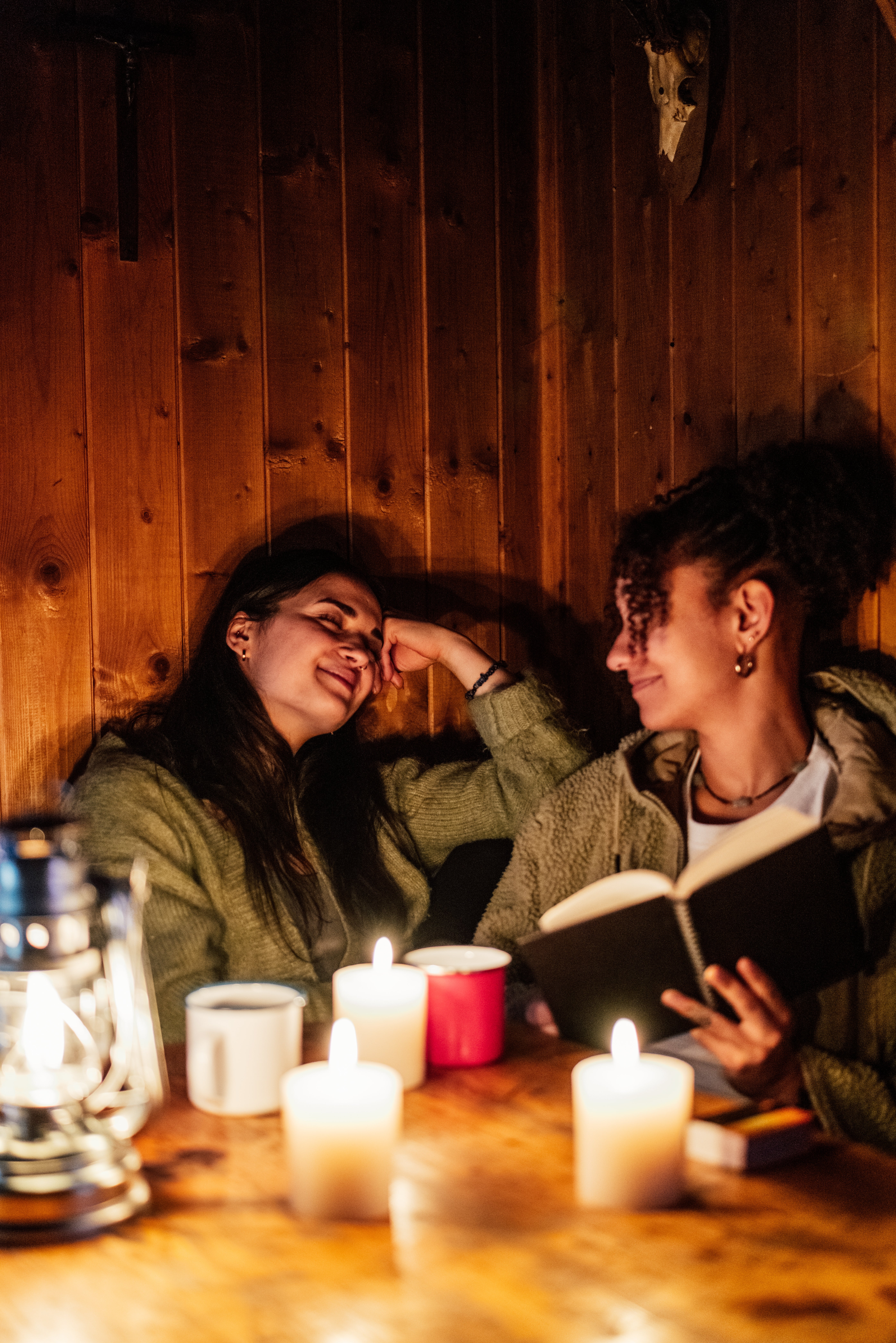 Two radical successful cozy sweaters beryllium astatine a candlelit table, 1 reads a book, smiling warmly astatine the other, creating an intimate atmosphere