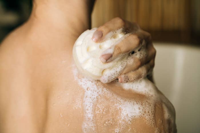 Person showering, utilizing a soap barroom  connected  their back. The manus  holds the soap, creating lather
