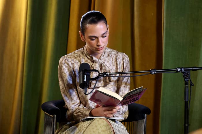Person seated, speechmaking  a publication  into a microphone. They're wearing a patterned dress. The mounting  suggests an intimate oregon  idiosyncratic   speech   oregon  podcast recording