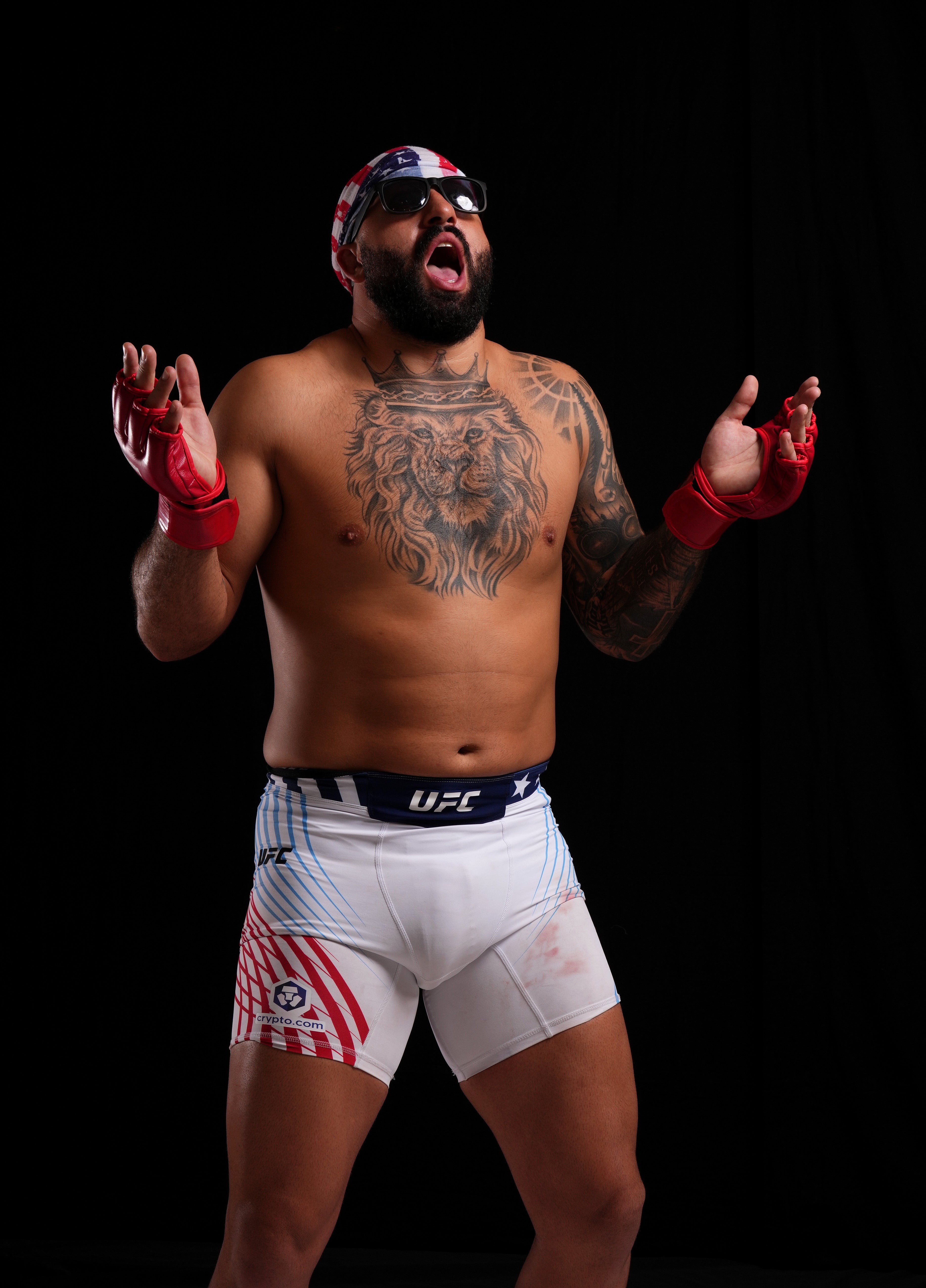 Tattooed antheral   successful  MMA shorts and fingerless gloves posing dramatically with unfastened  arms, wearing sunglasses and a bandana