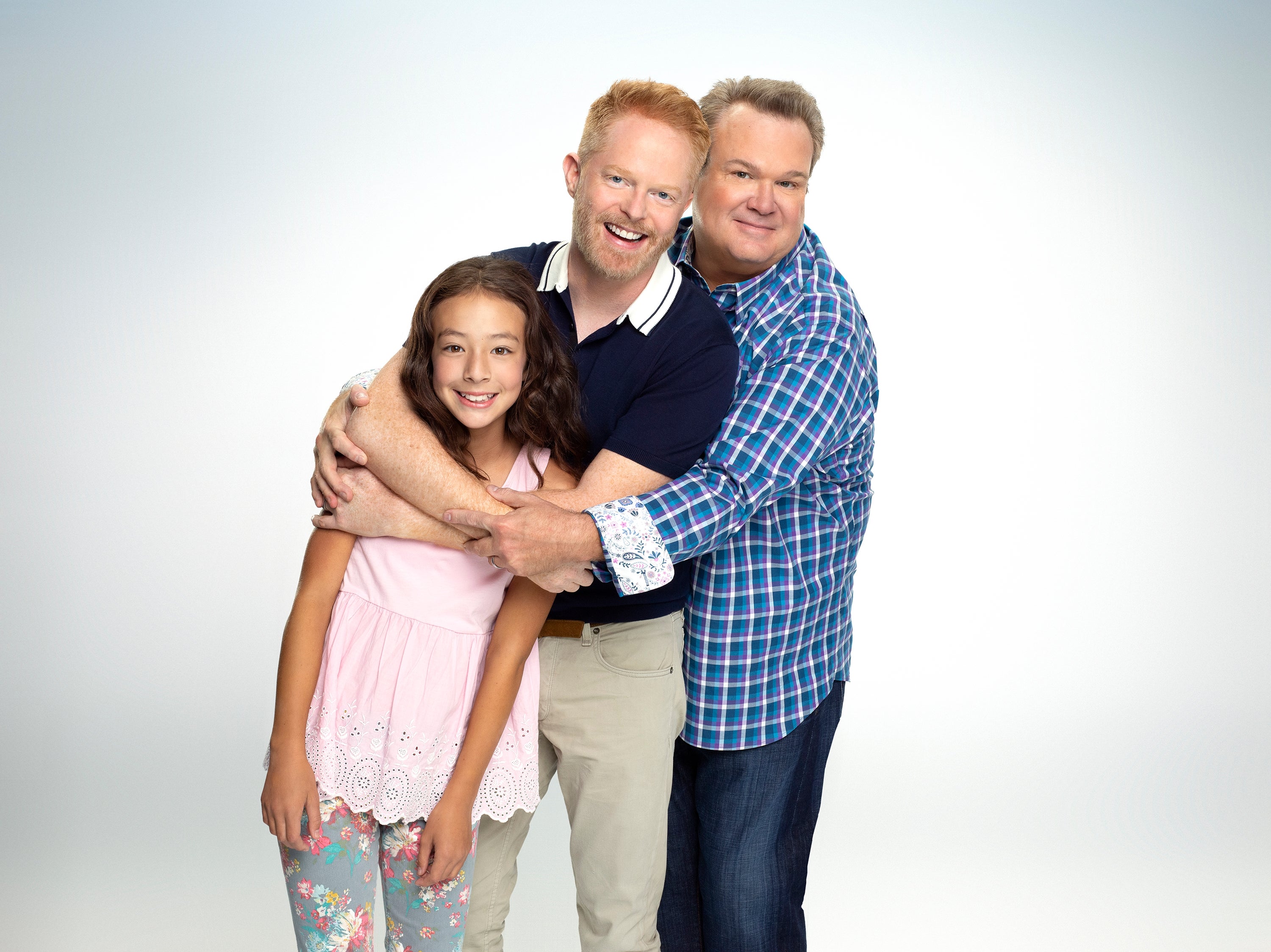Three radical   airs  together, smiling. One is simply a kid  successful  casual wear, and 2  adults, 1  successful  a polo and different  successful  a checkered shirt, clasp  her