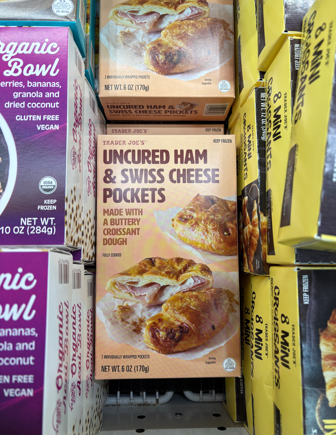 Box of Trader Joe's Uncured Ham &amp;amp; Swiss Cheese Pockets in a display of other food items. Packaging shows a flaky pastry image